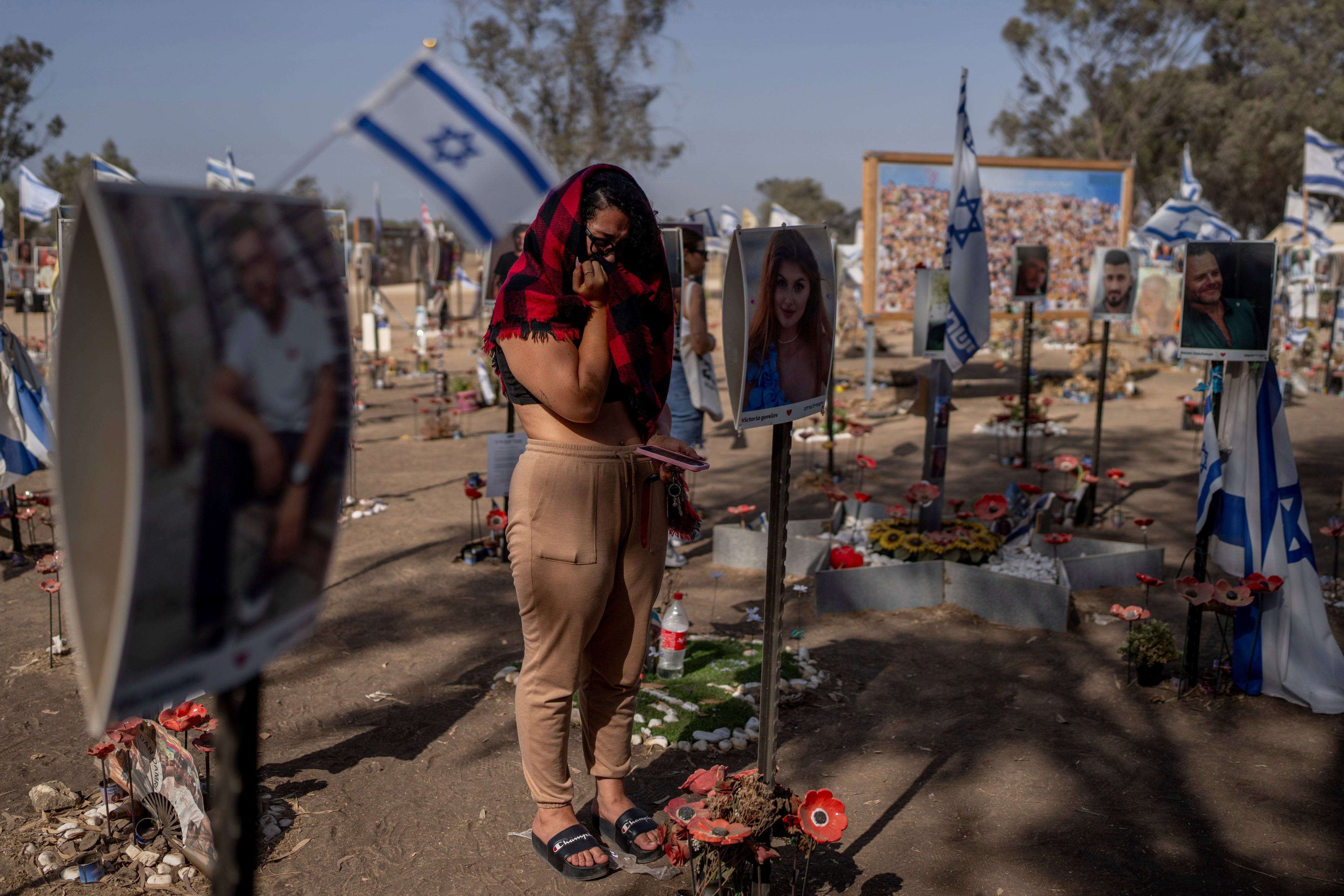 A woman stands next to photos of people killed and taken captive by Hamas militants during their violent rampage through the Nova music festival in southern Israel. Photo: AP