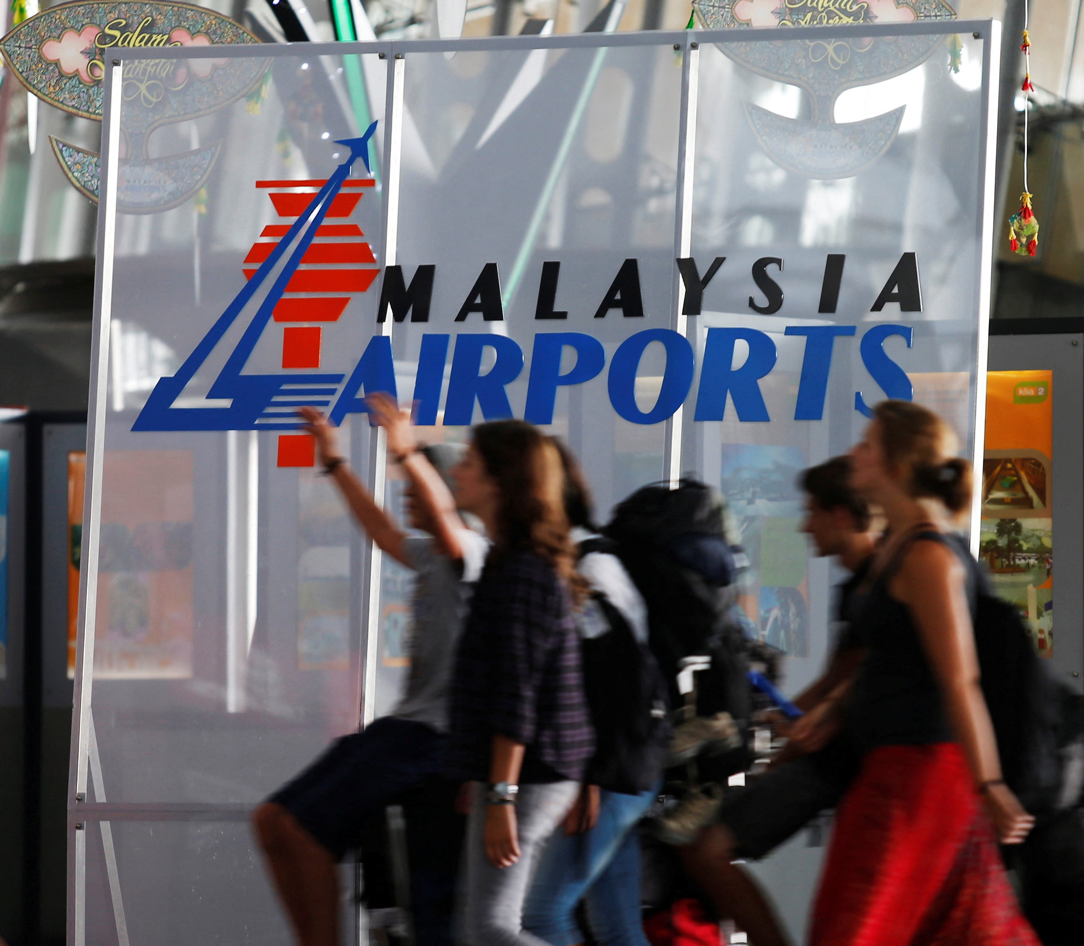 Travellers walk past a logo of Malaysia Airports Holdings Berhad at the departure hall of Kuala Lumpur International Airport. Photo: Reuters