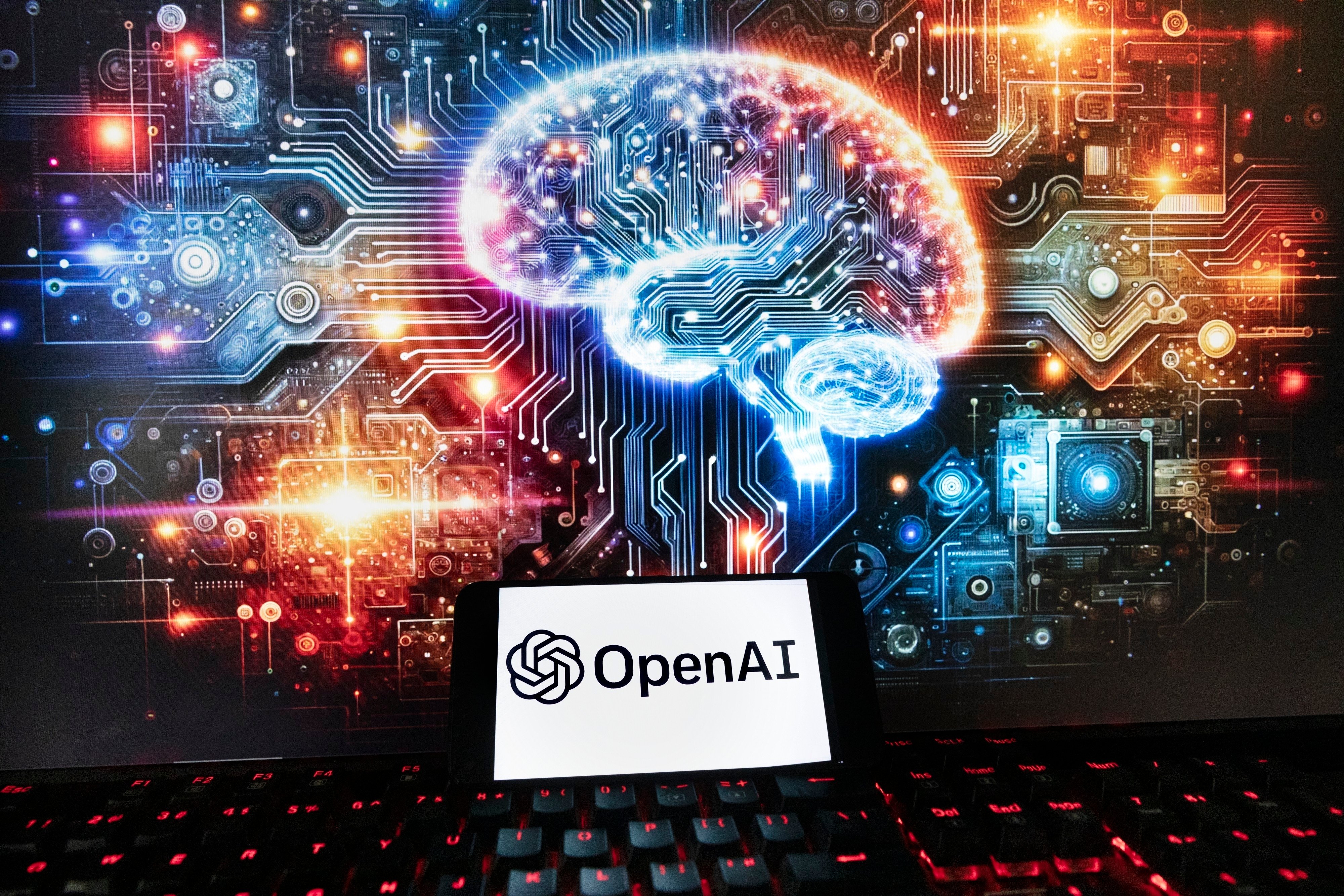 The OpenAI logo is displayed on a smartphone with an image on a computer monitor generated by ChatGPT’s Dall-E text-to-image model, Dec. 8, 2023. Photo: AP