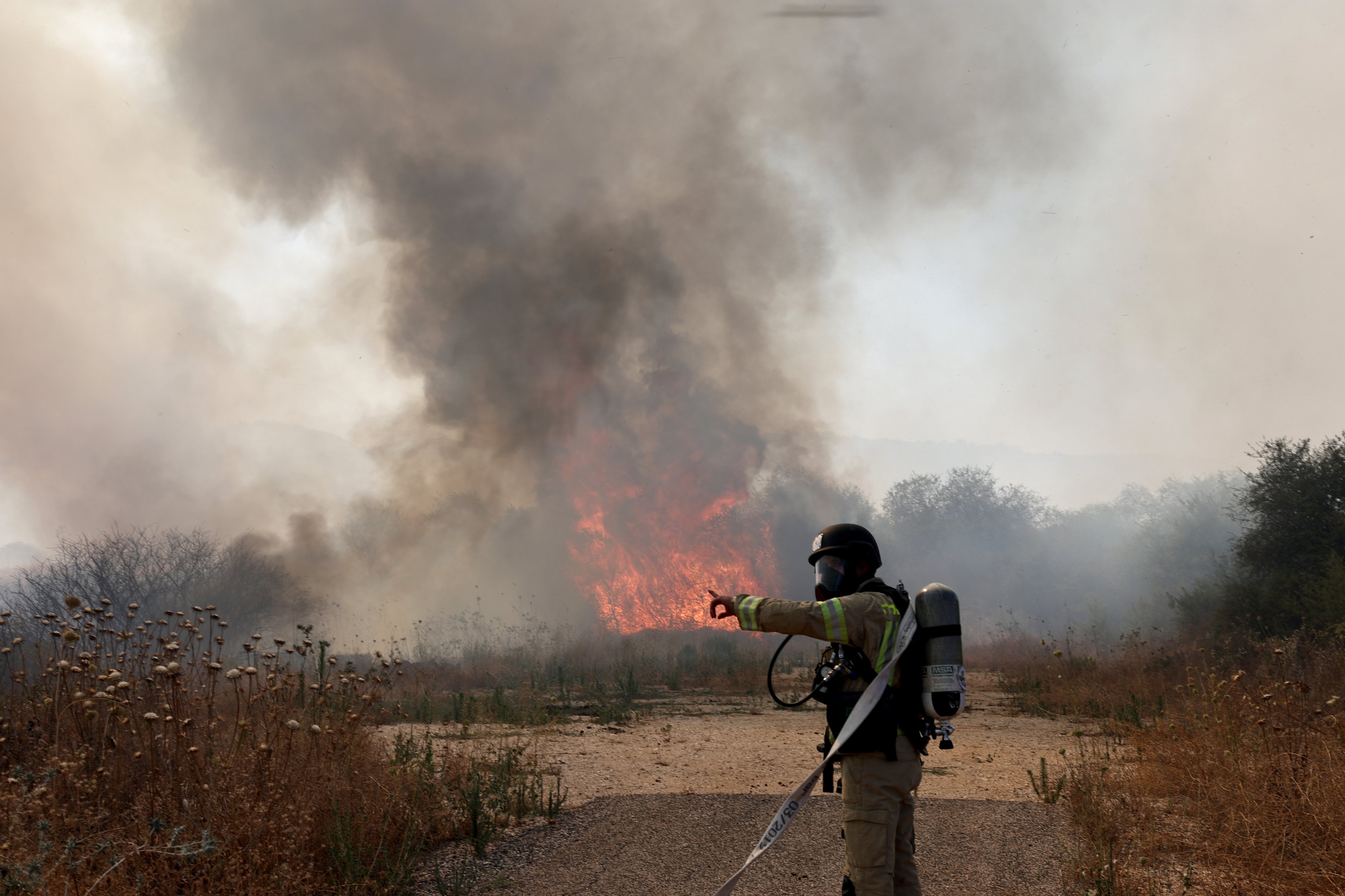 A firefighter douses a fire after Israeli forces intercepted an aerial target that crossed from Lebanon into northern Israel on Tuesday. Photo: EPA-EFE