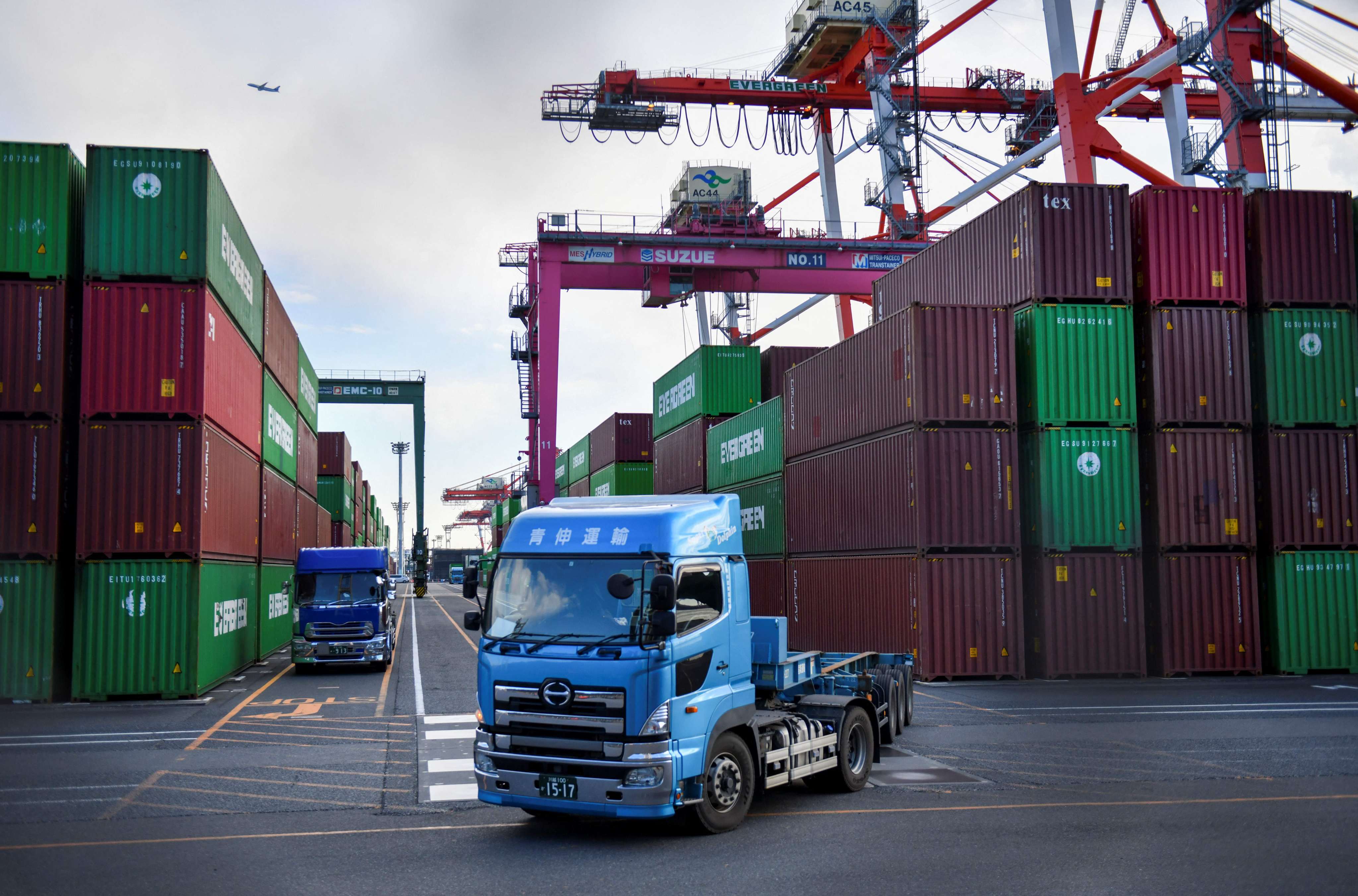 A truck pulls out of a port in Tokyo as cargo containers are loaded on and off vehicles. Photo: AFP