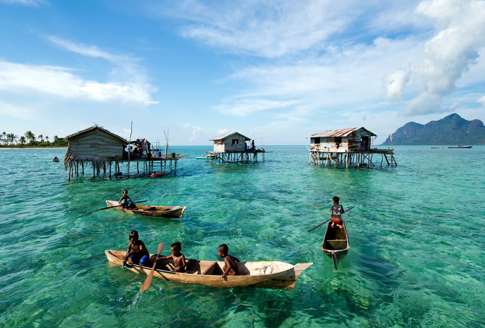 Young Bajau laut children paddling a boat near stilted houses off the coast of Borneo. Photo: Shutterstock