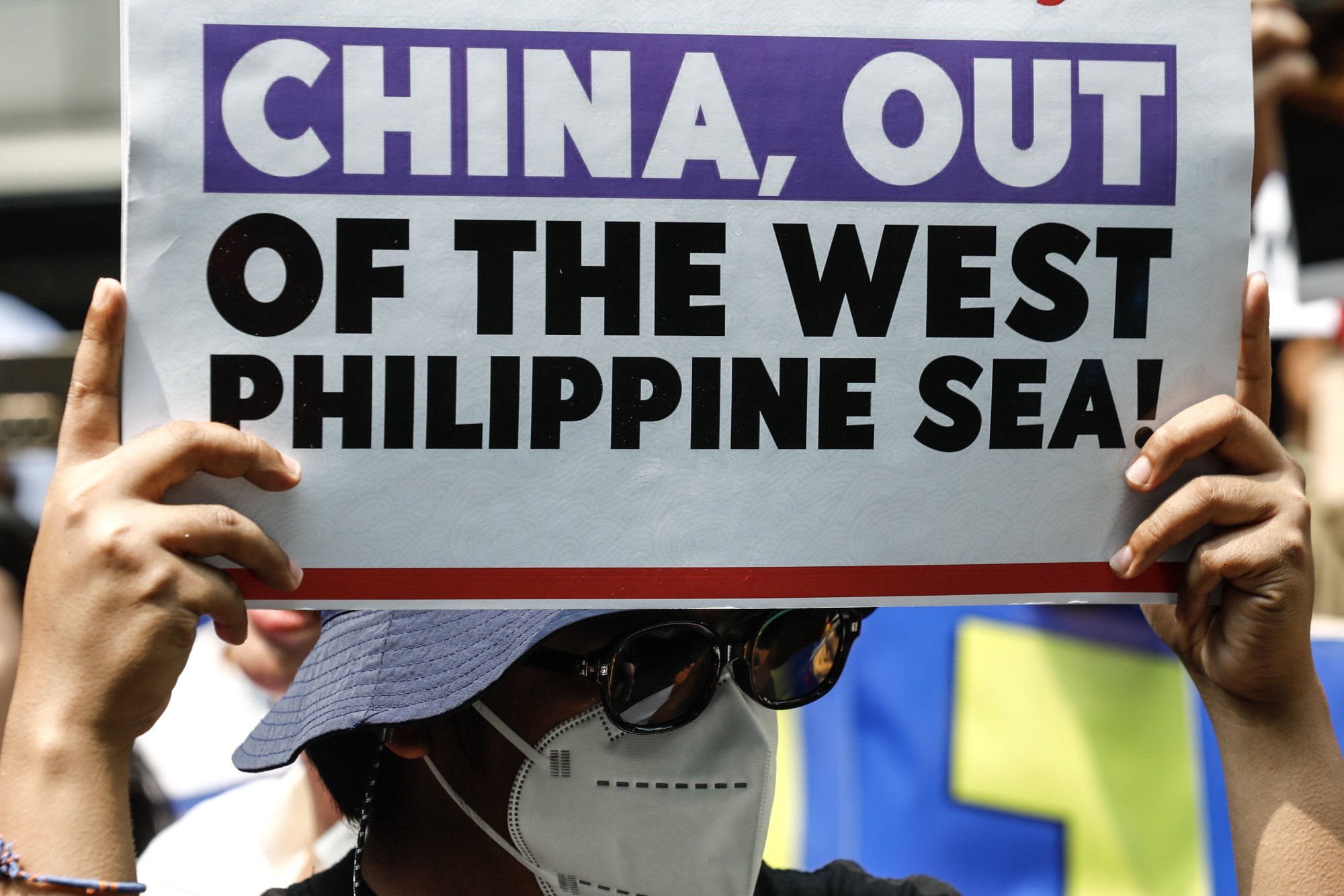 A protester holds a sign criticising China’s harassment of Philippine ships in the South China Sea, at a rally outside China’s consular office in Makati City, Metro Manila. Photo: EPA-EFE