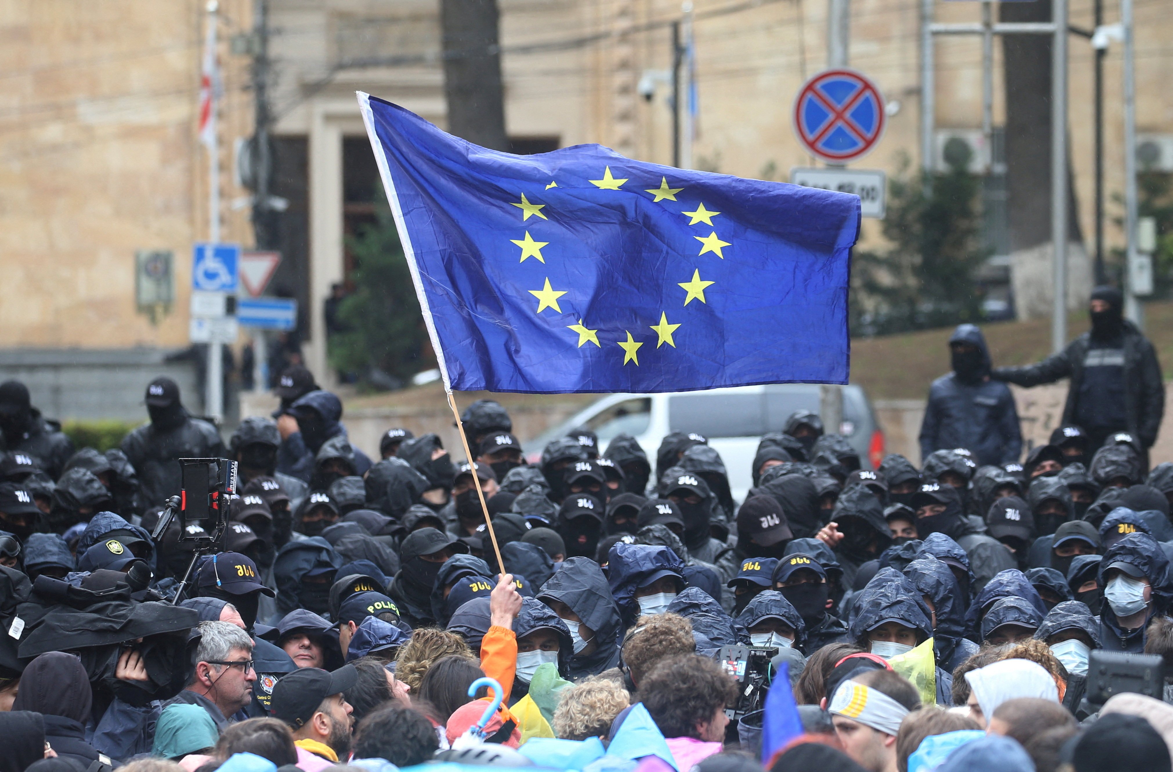 A demonstrator holds a European Union flag in front of law enforcement officers during a rally to protest against a bill on “foreign agents” in Tbilisi in May. Photo: Reuters