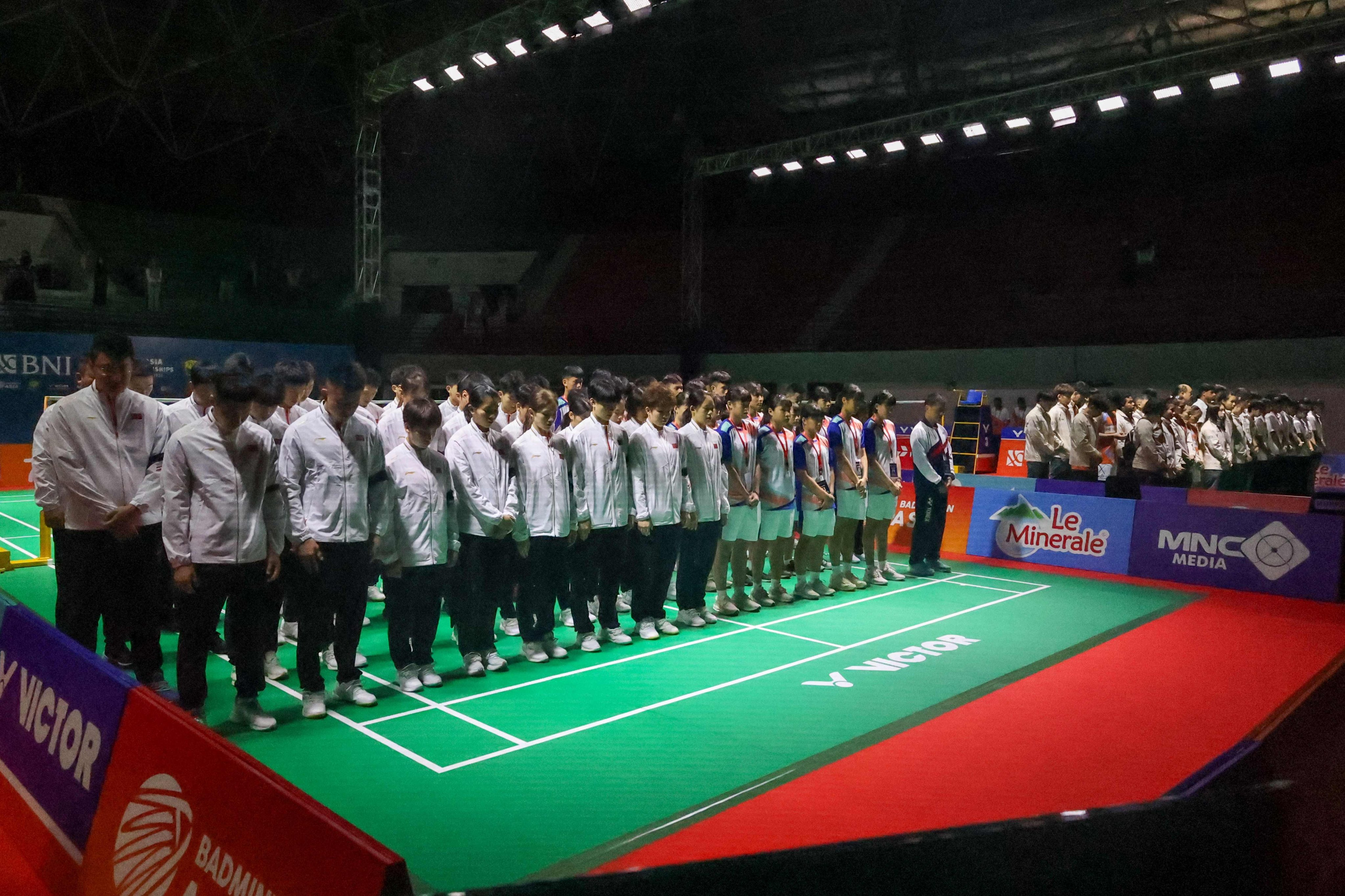 Chinese badminton players and coaches (in white jackets and black armbands) show their respect following the death of Zhang Zhijie. Photo: AFP