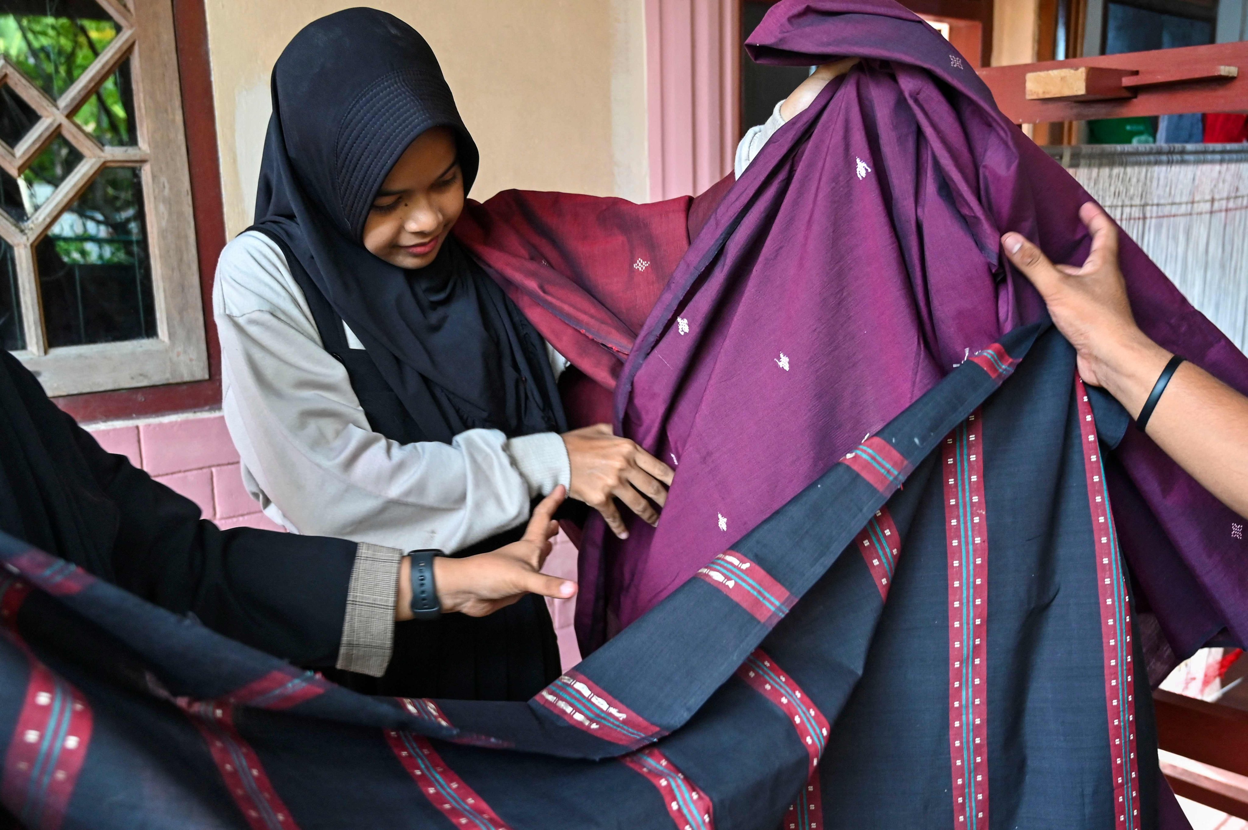 An employee displays traditional textiles in Lhoknga, Aceh province on June 24. The labour-heavy textile sector employs around 3.9 million people in Indonesia. Photo: AFP