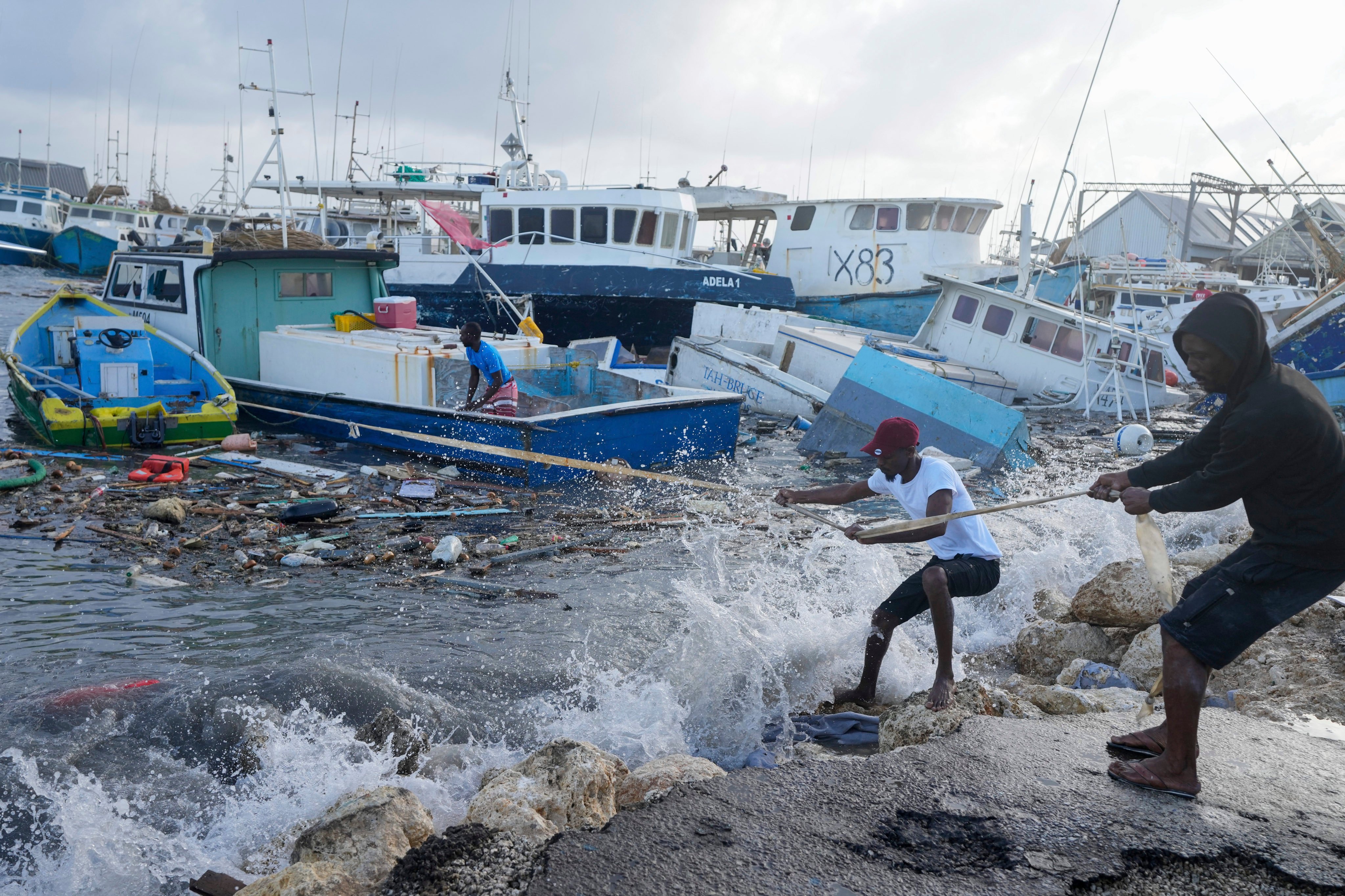 Fishermen pull a boat damaged by Hurricane Beryl back to the dock at the Bridgetown Fisheries in Barbados on Monday. Photo: AP