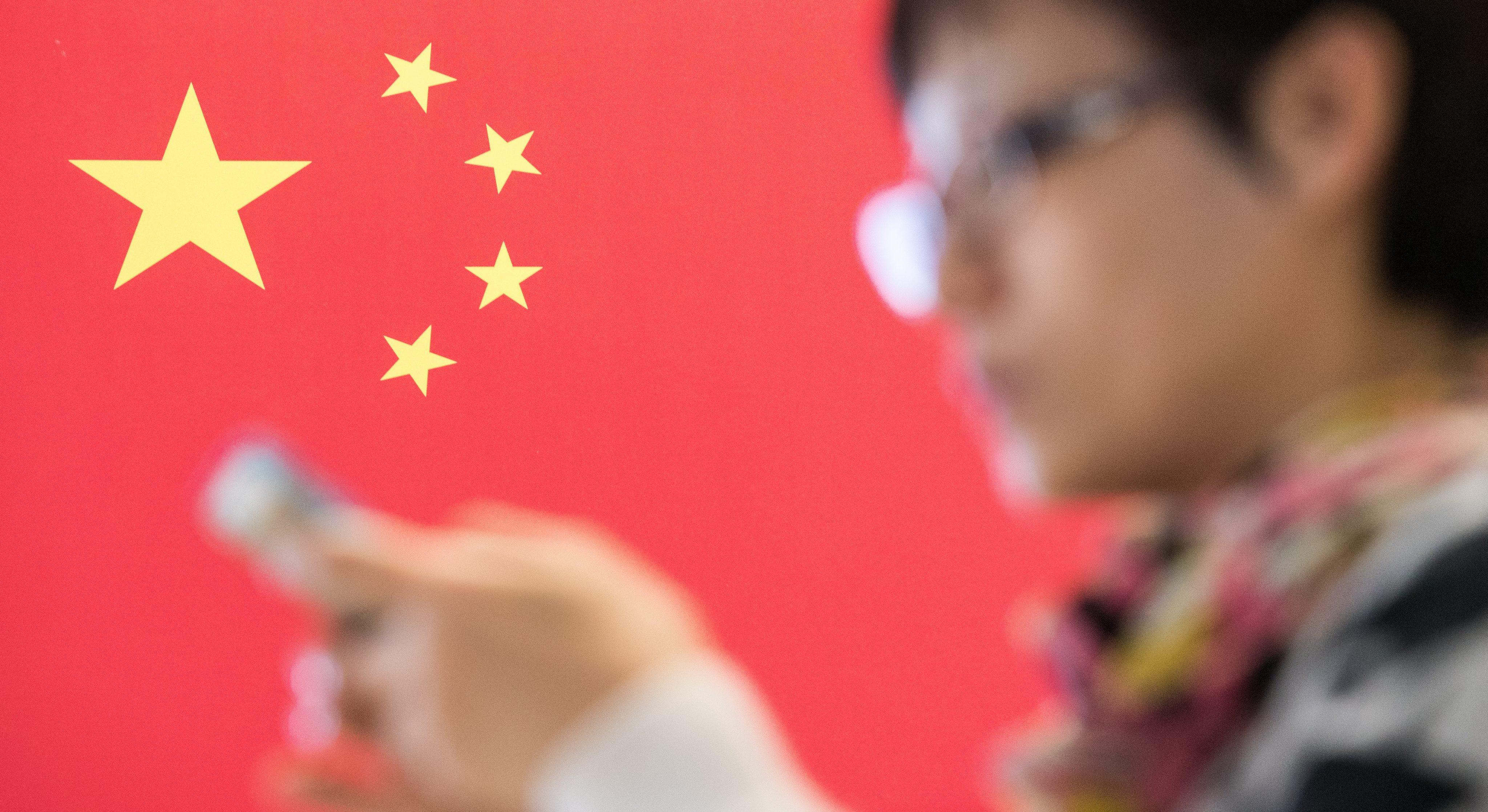 A woman checks her smartphone in front of a Chinese flag at a computer fair in Hanover, Germany, in March 2015. Ultranationalist views are increasingly being aired on Chinese social media, leading to real-life consequences. Photo: EPA