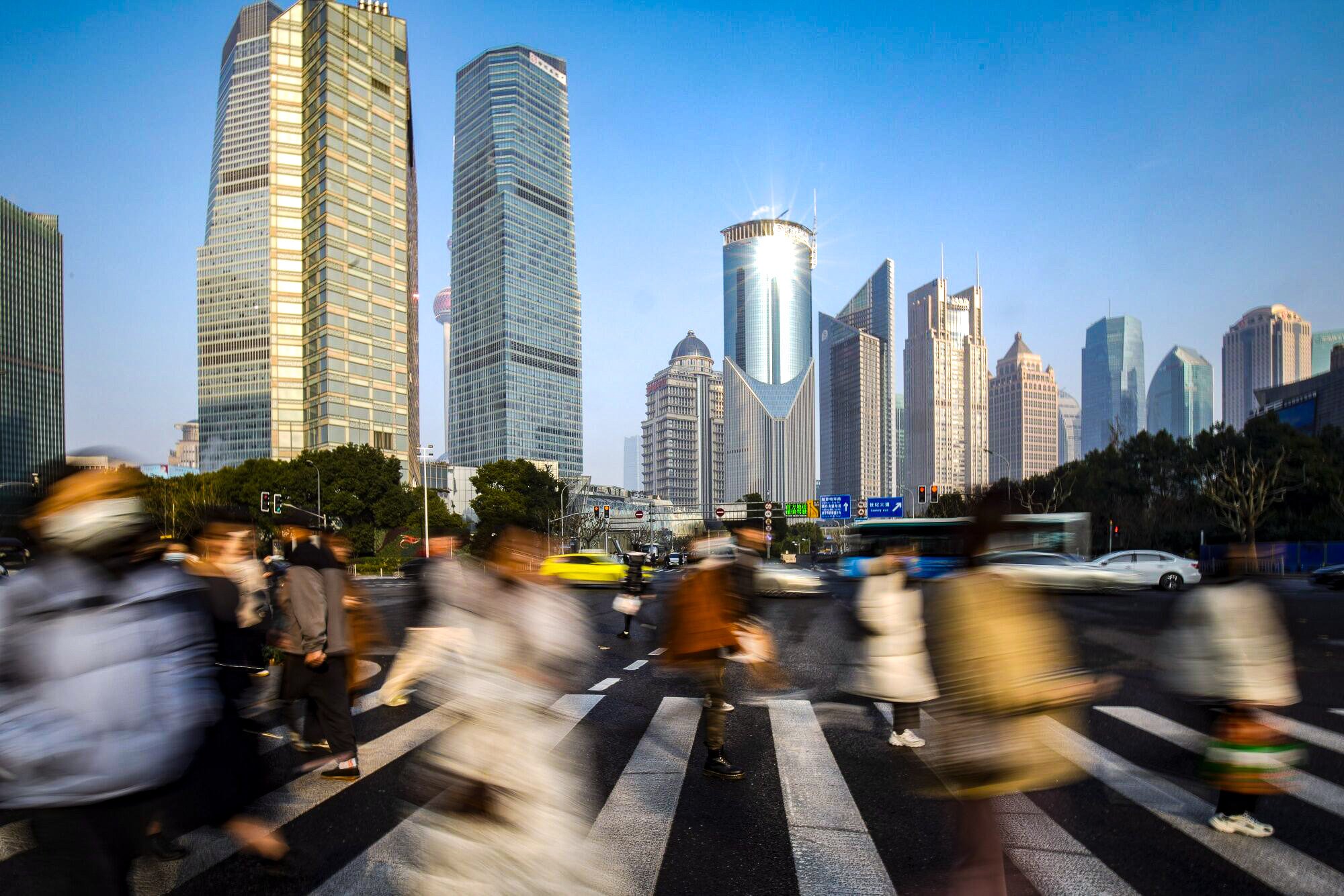 Pedestrians cross a road in the Lujiazui financial district in Shanghai. China is planning to cap the salaries of finance executives. Photo: Bloomberg