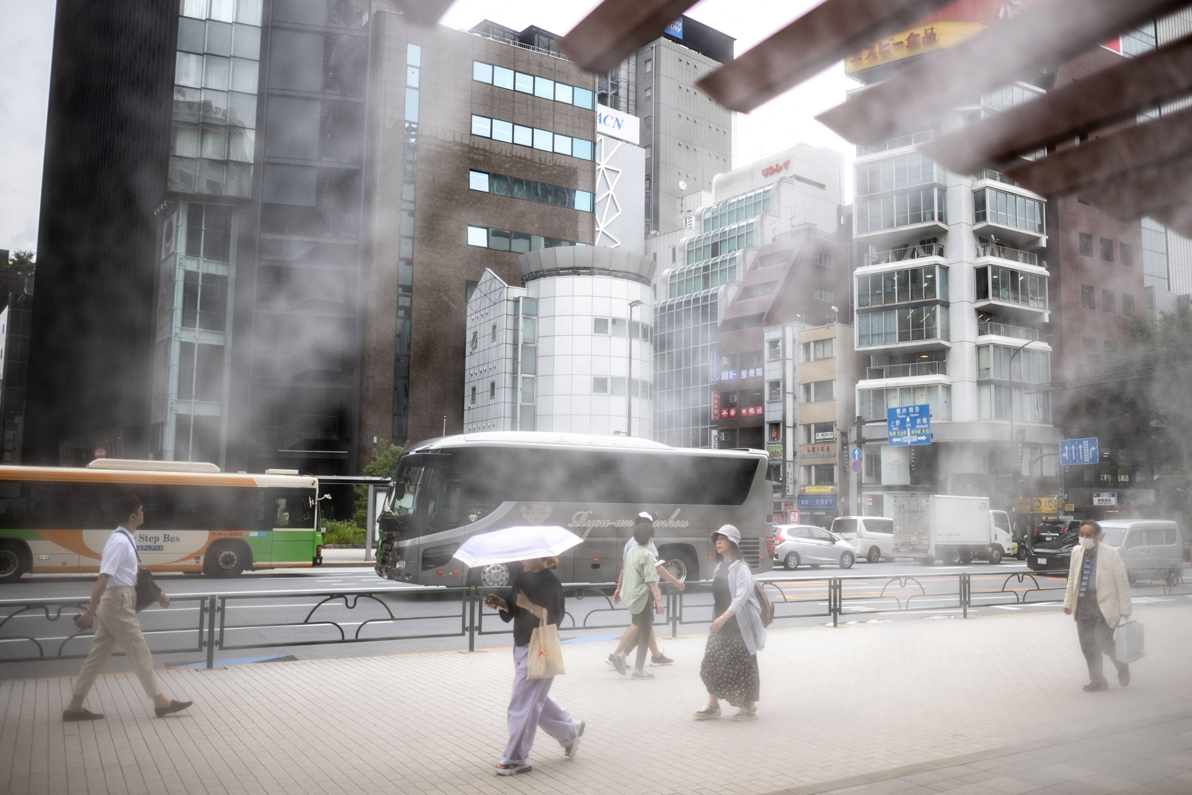 People walk in front of an overhead water misting system on a hot day in Tokyo’s Ginza district on July 2. Photo: AFP