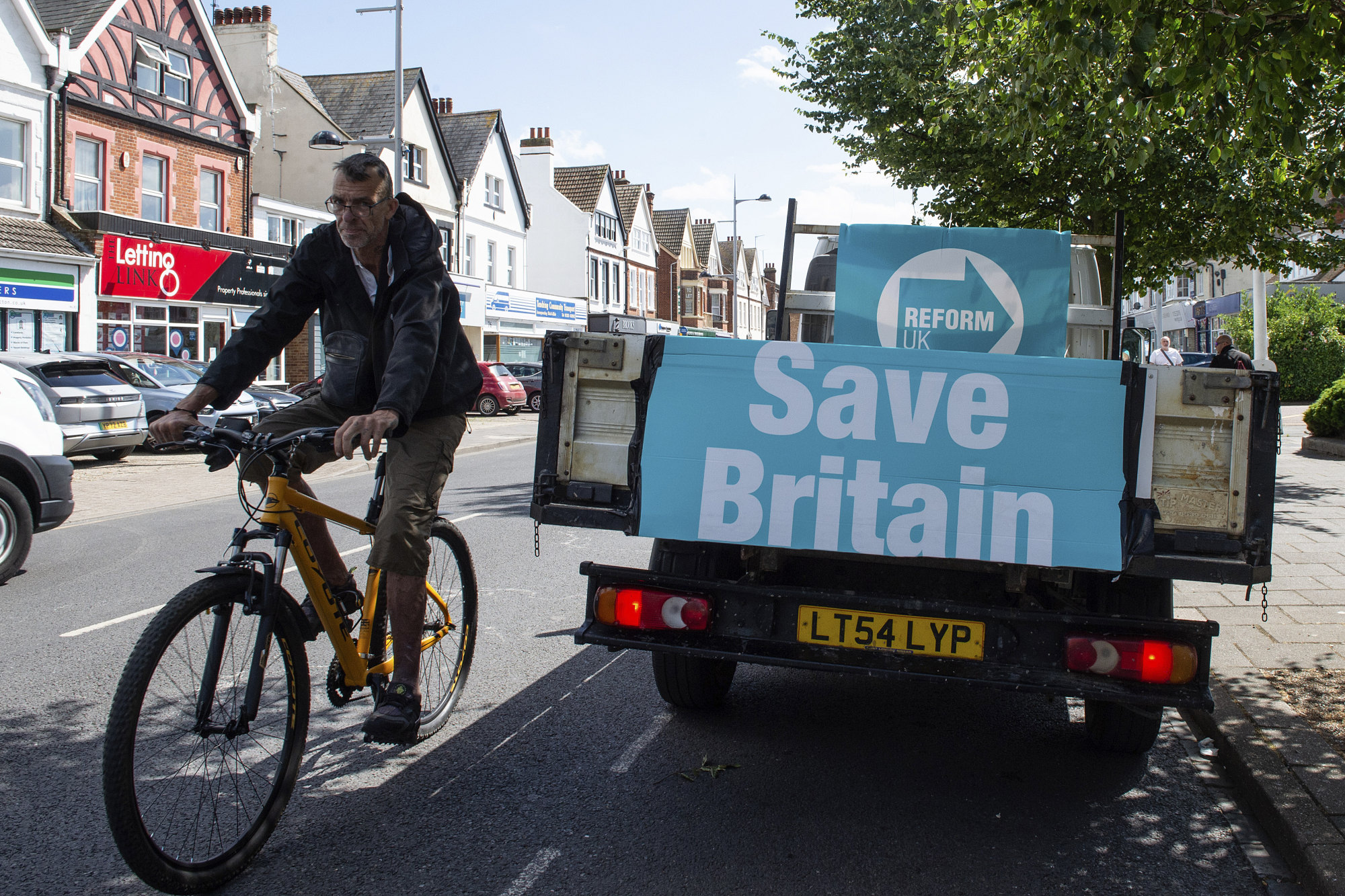 A cyclist passes a van with advertising for the Reform UK Party in Clacton On Sea, England on July 4. Photo: AP