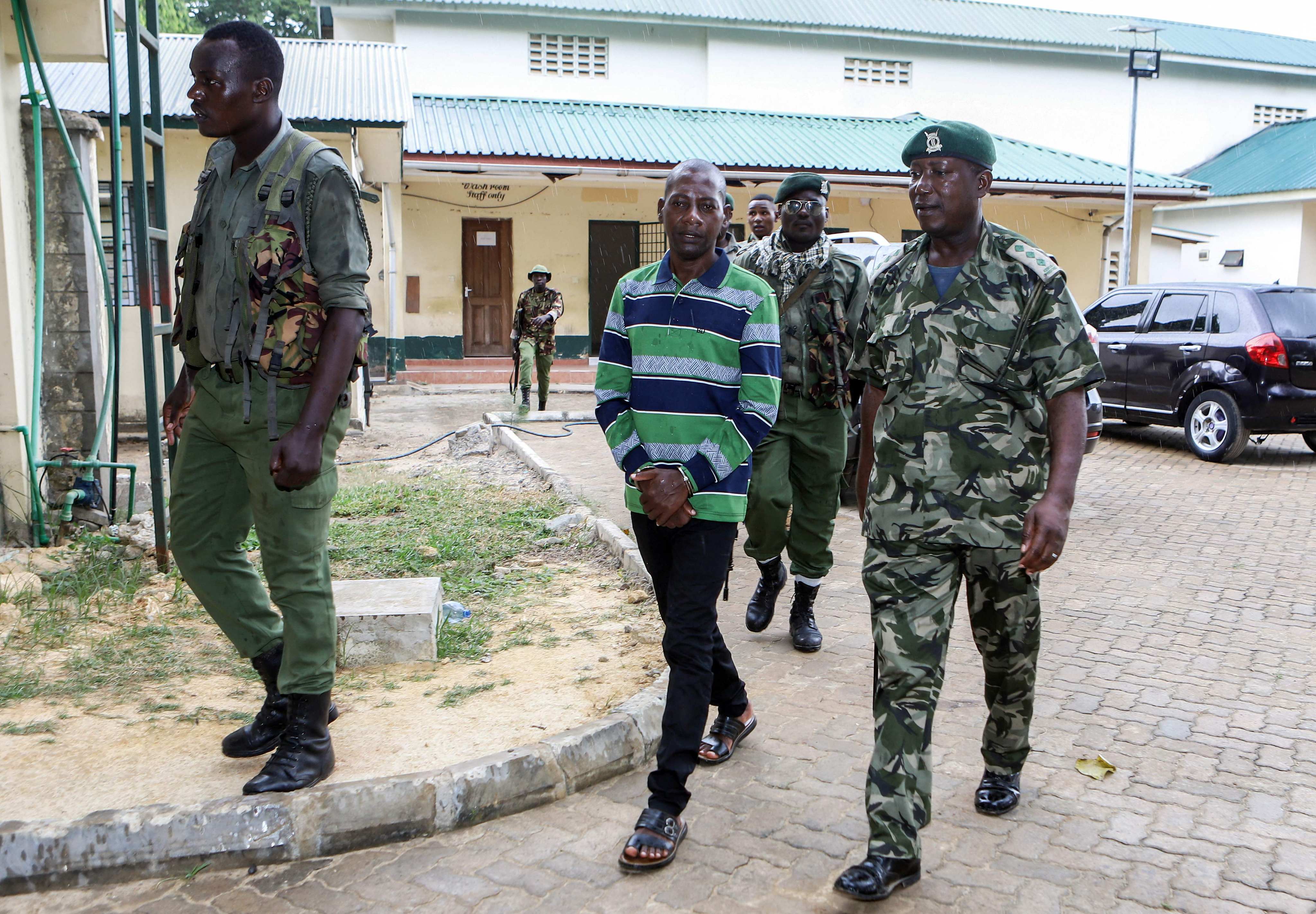 Self-proclaimed pastor Paul Nthenge Mackenzie (left) is surrounded by Kenya Police Officers as he appears at the Shanzu Law Courts in Mombasa on January 18, 2024. Photo: AFP/File