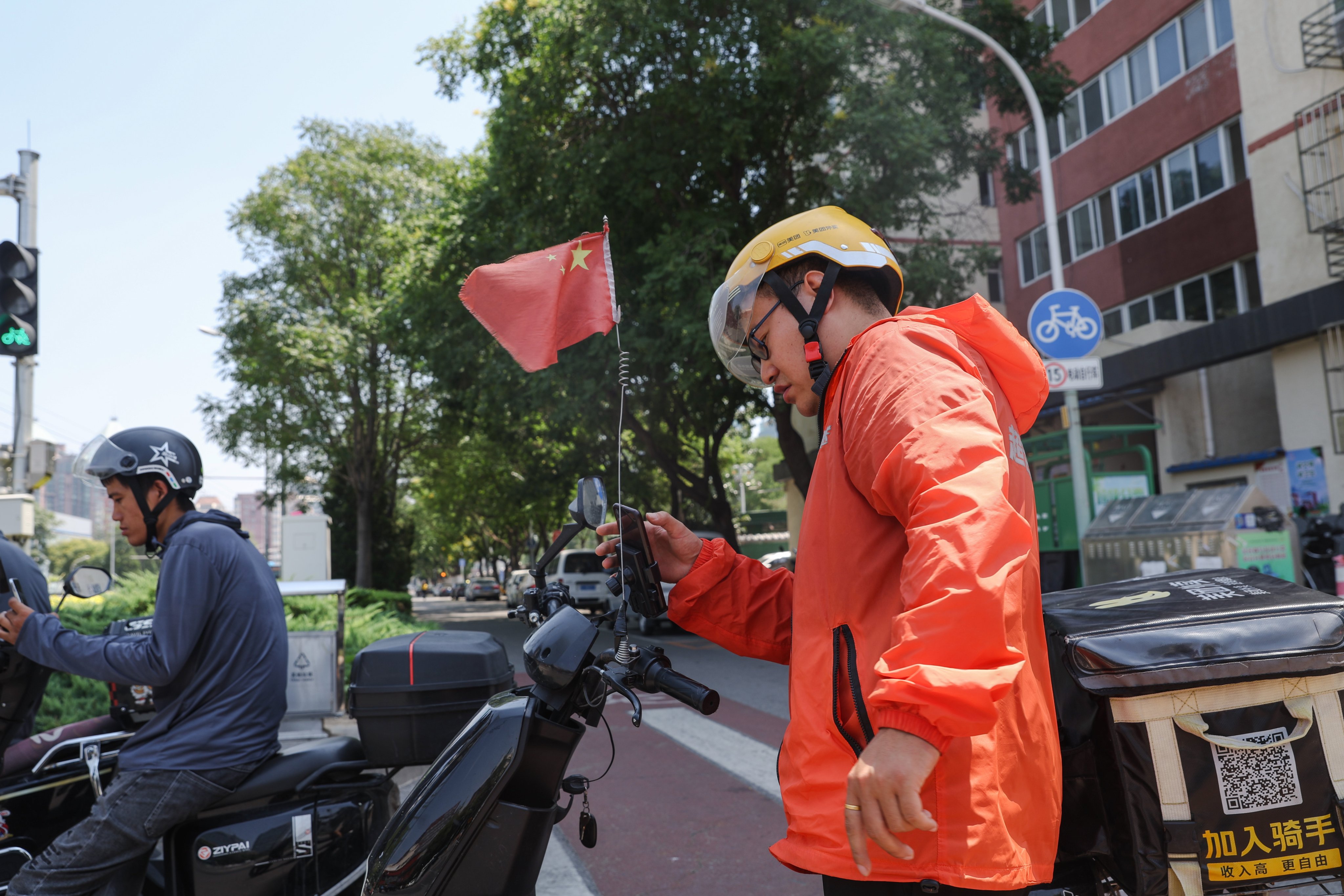 A delivery man uses his cellphone on a street in Beijing. Photo: EPA-EFE
