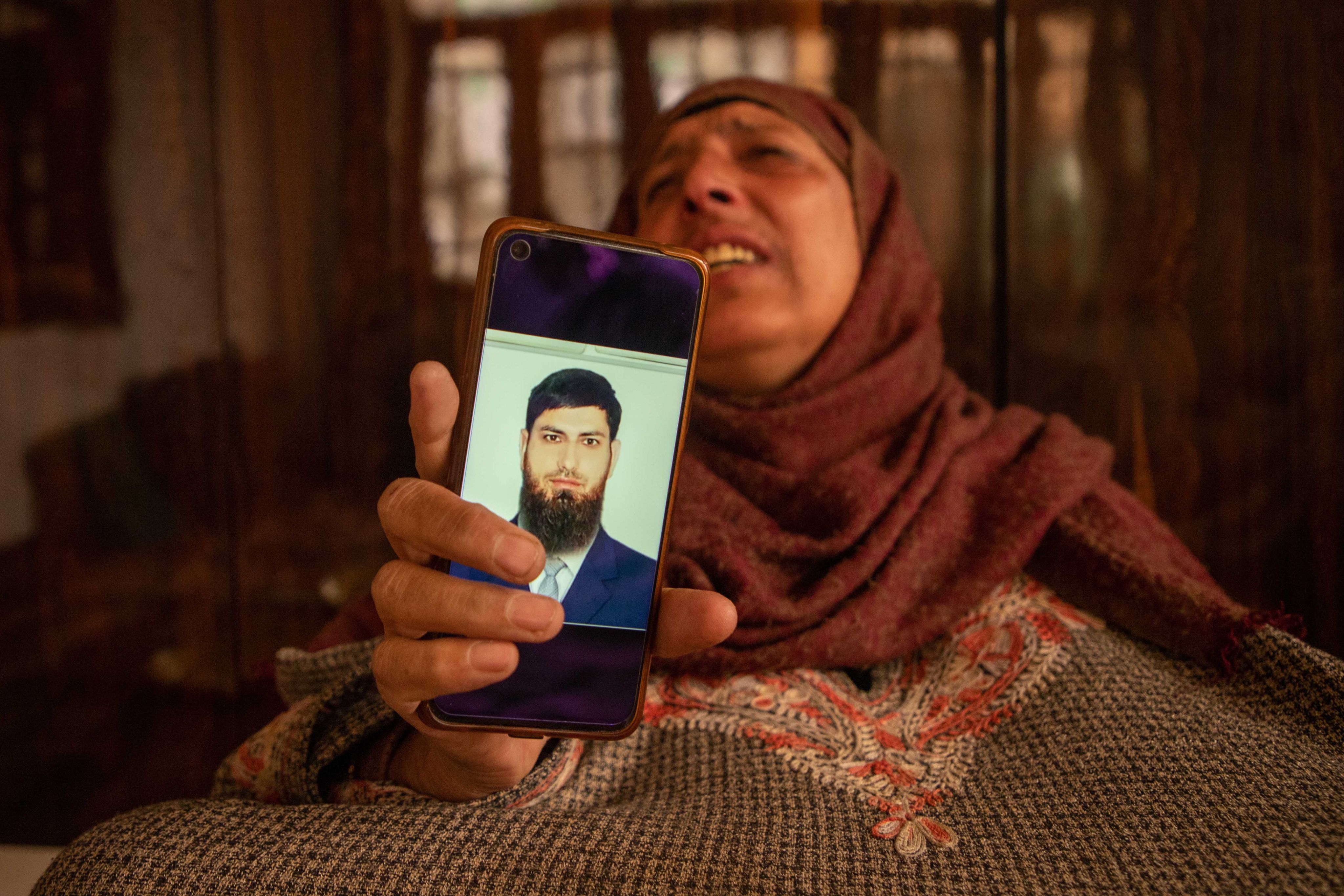 Raja Banu, 60, shows a picture of her son Aazad. According to his family, Aazad was misled into fighting for Russia in its war in Ukraine. Photo: Umer Asif