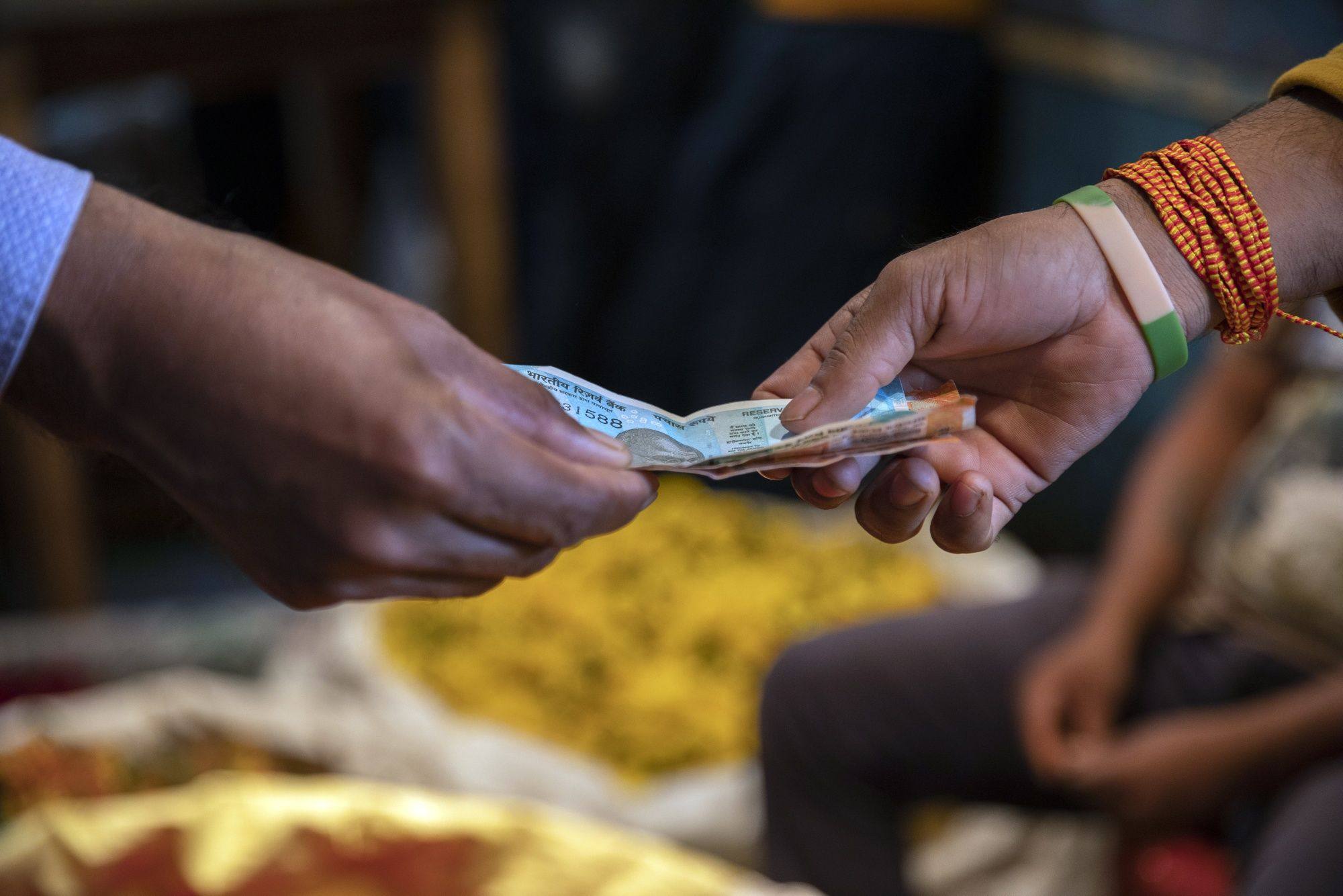 A customer and vendor exchange Indian rupee banknotes in Bengaluru. India is one of many countries dealing with high inflation. Photo: Bloomberg