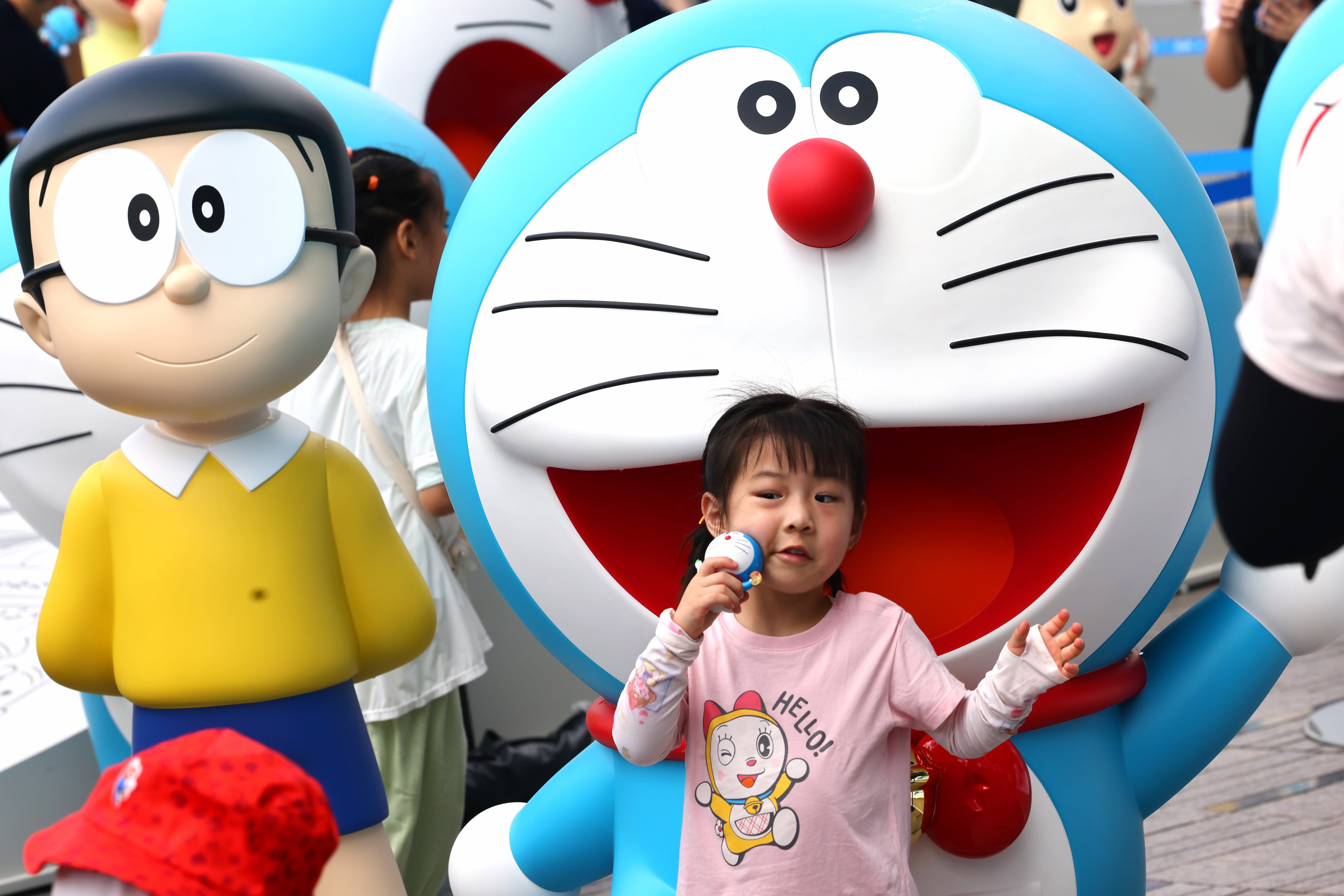 A young Doraemon fan poses for a picture alongside a statue of the beloved robot cat. Photo: Dickson Lee