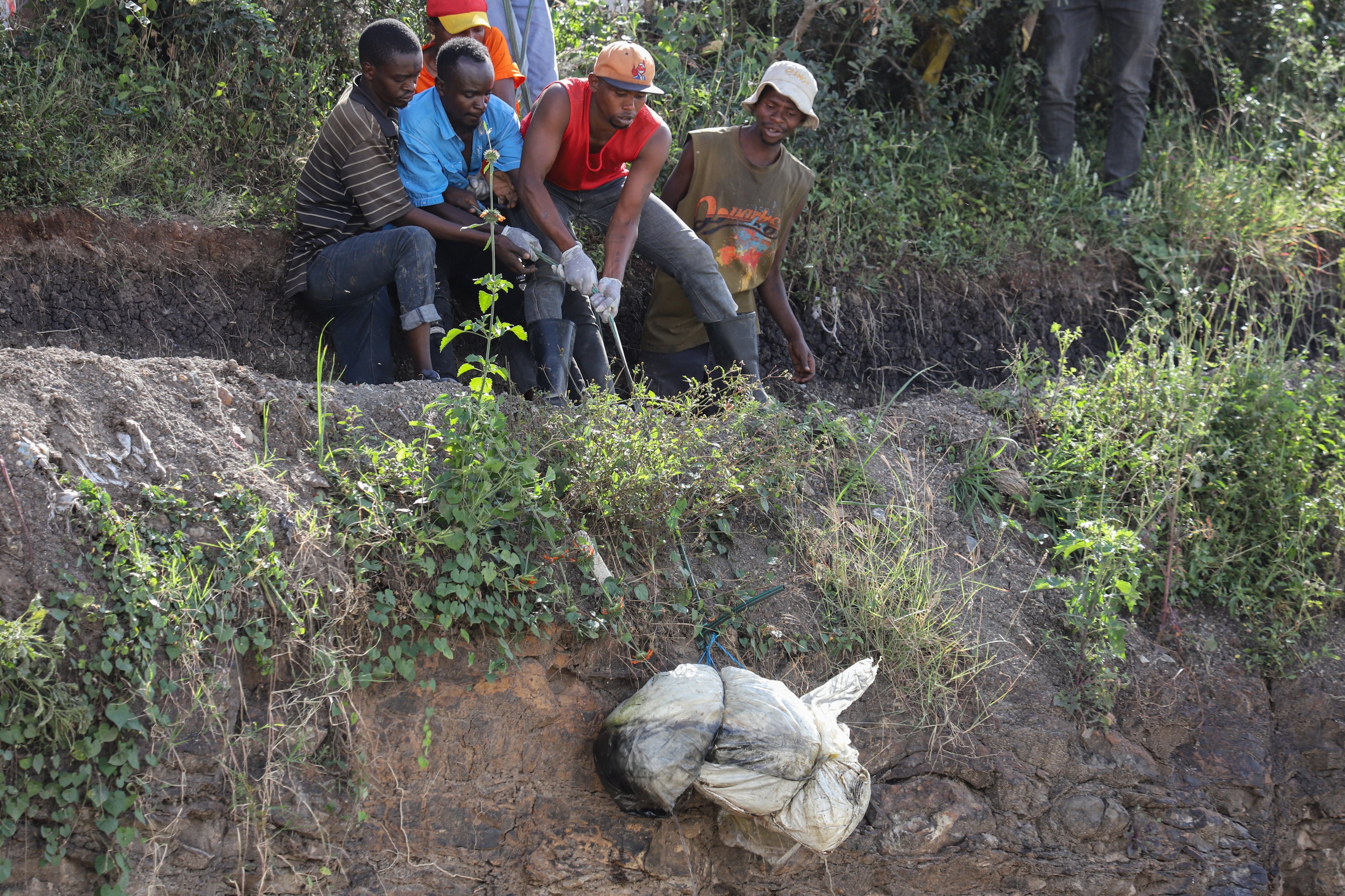 A group of men retrieve a body wrapped in a bag from a quarry-turned-dumpsite in Nairobi, Kenya, on Friday. Photo: EPA-EFE