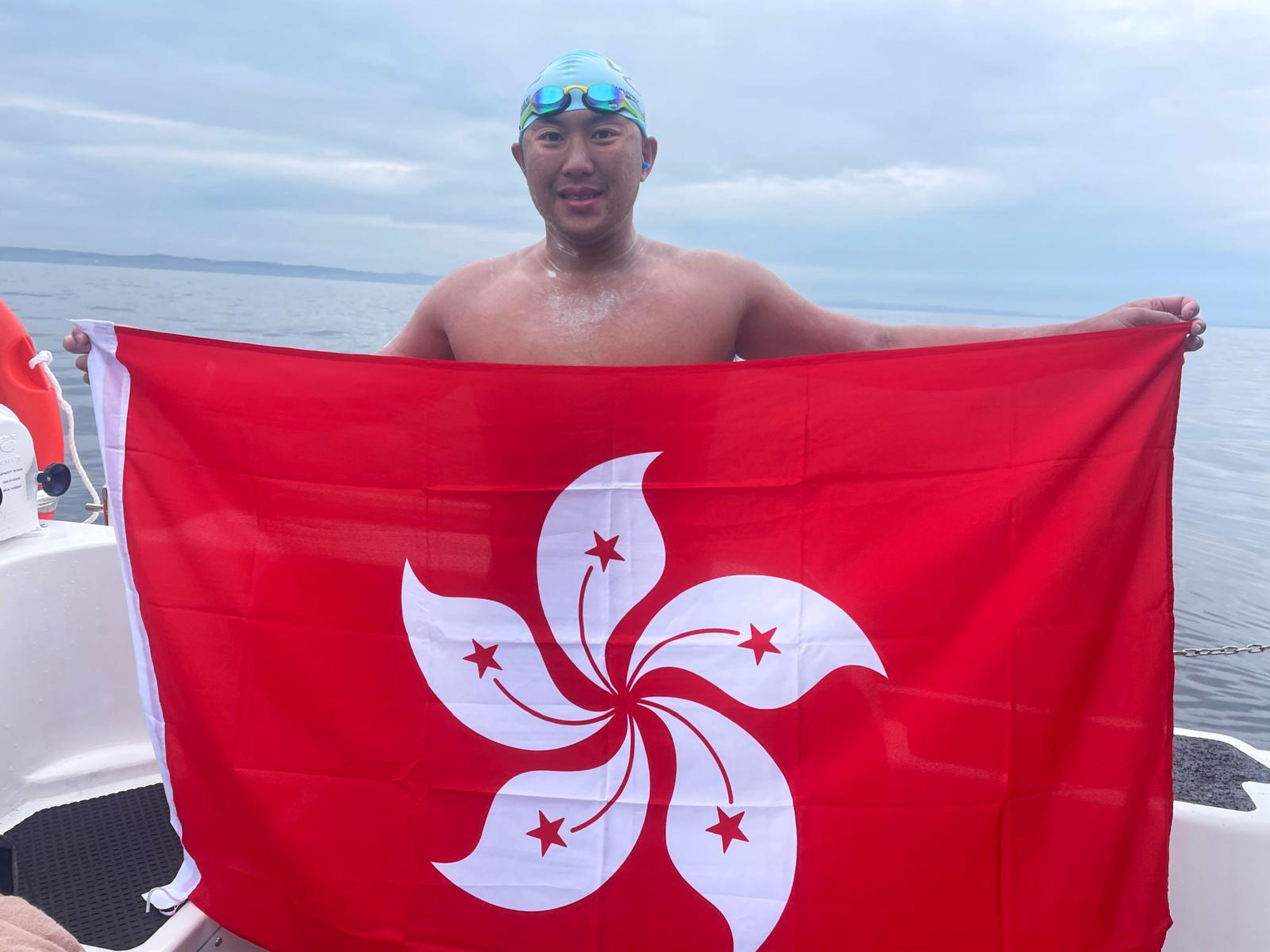 Ryan Leung holds up the Hong Kong flag in Portpatrick on the west coast of Scotland after completing a gruelling 40km swim from Northern Ireland. Photo: Handout