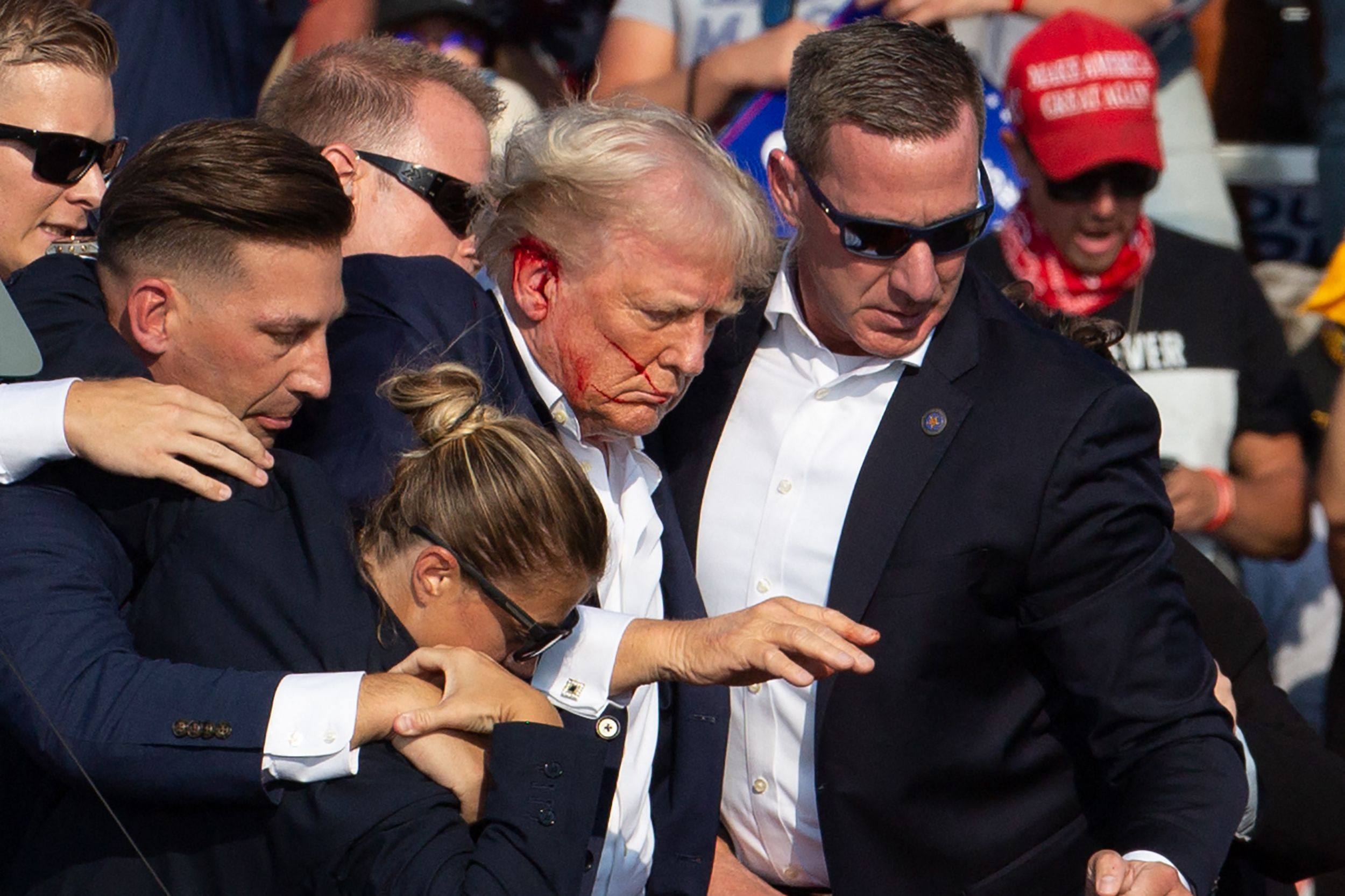 US Republican candidate Donald Trump is seen with blood on his face surrounded by secret service agents as he is taken off the stage in Butler, Pennsylvania, on Saturday. Photo: AFP