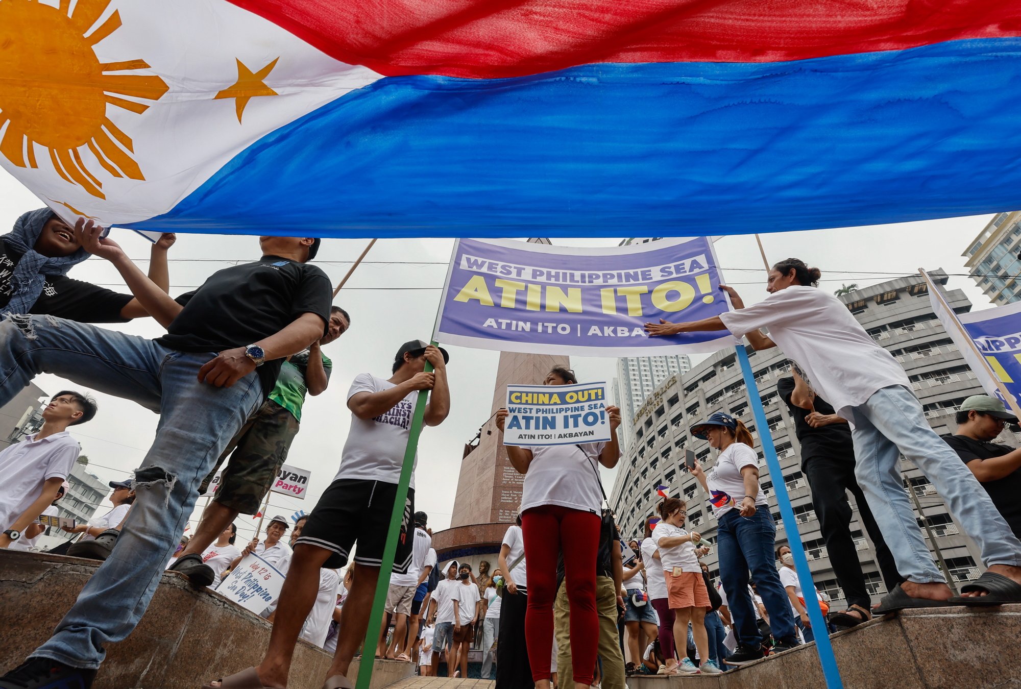 Protesters hold a Philippine flag and signs defending Philippine sovereignty in areas of the South China Sea. Photo: EPA-EFE