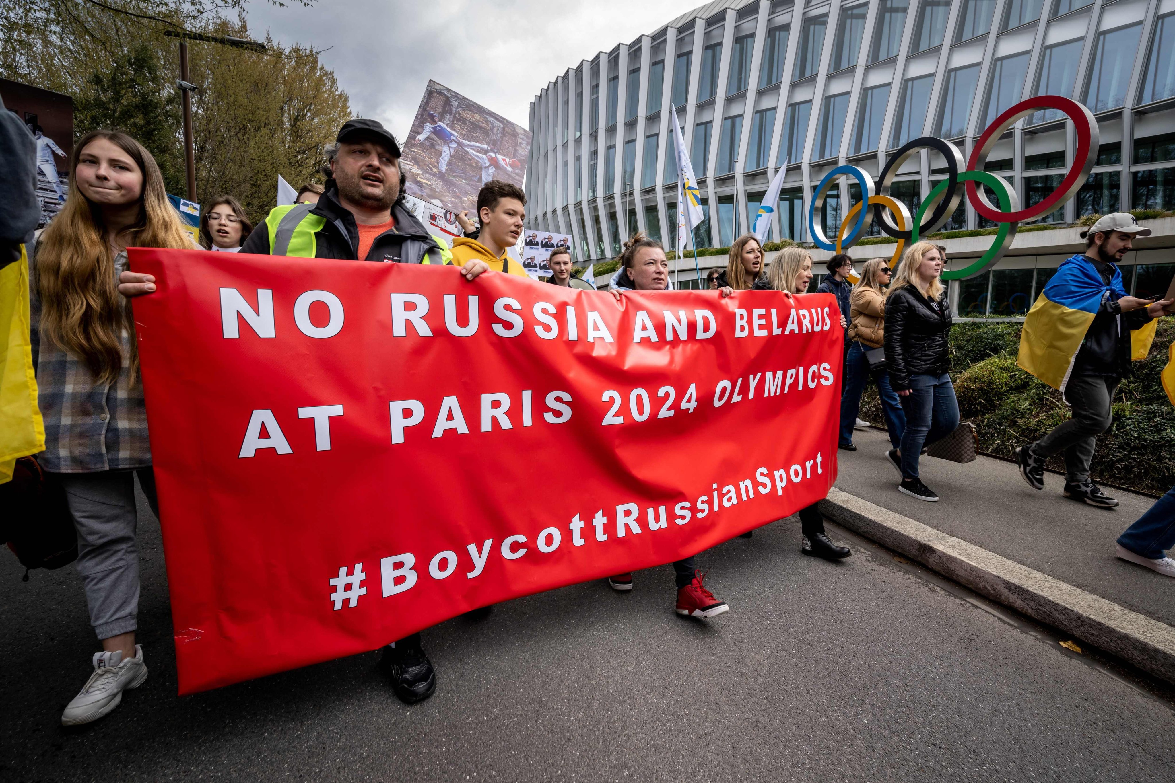 Protestors walk past the headquarters of International Olympic Committee urging against the return to competition of Russian athletes to compete under a neutral flag. Photo: AFP