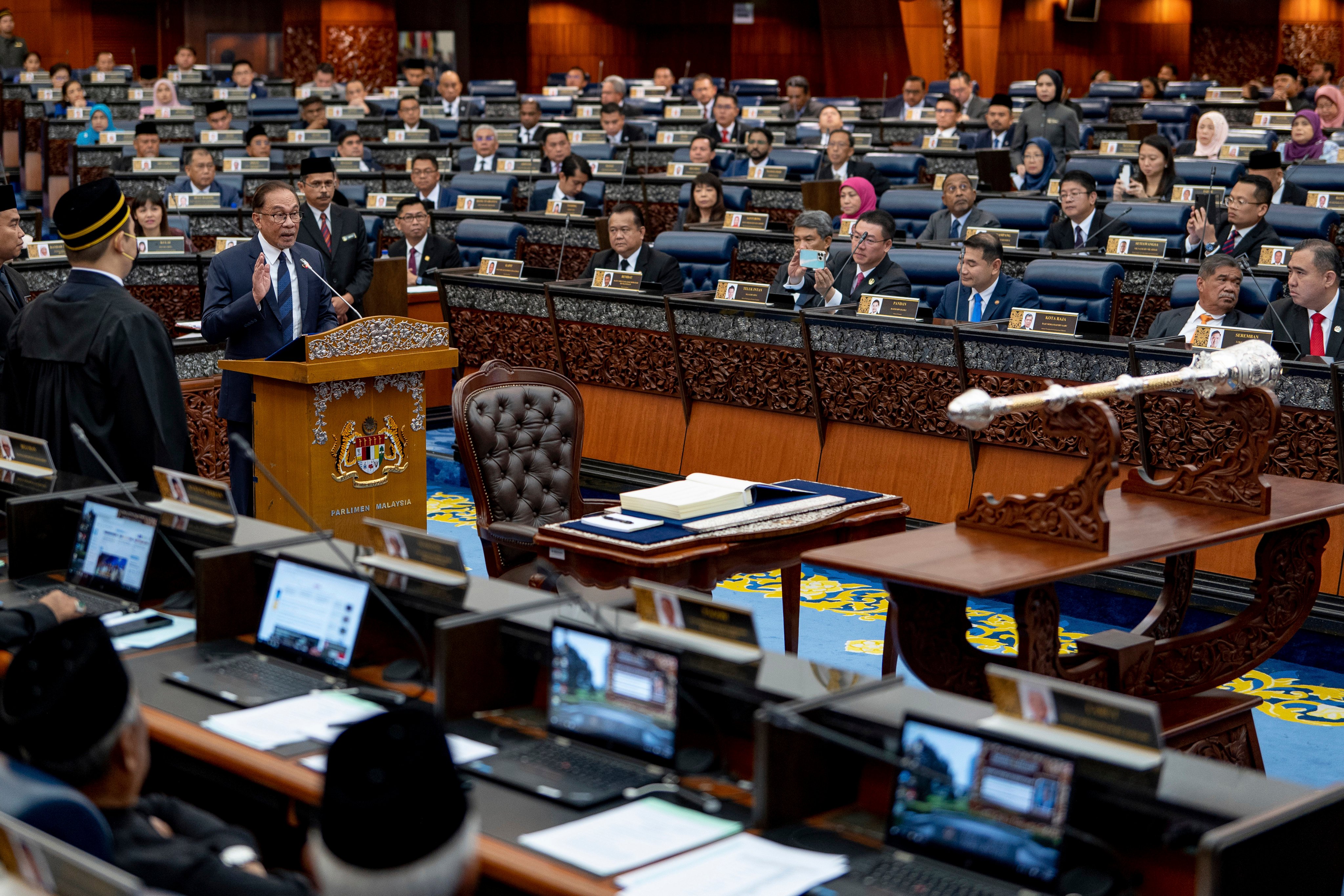 Malaysia’s Prime Minister Anwar Ibrahim, standing at center, takes his oath at the parliament in Kuala Lumpur on December 19, 2022. Photo: Prime Minister’s office via AP