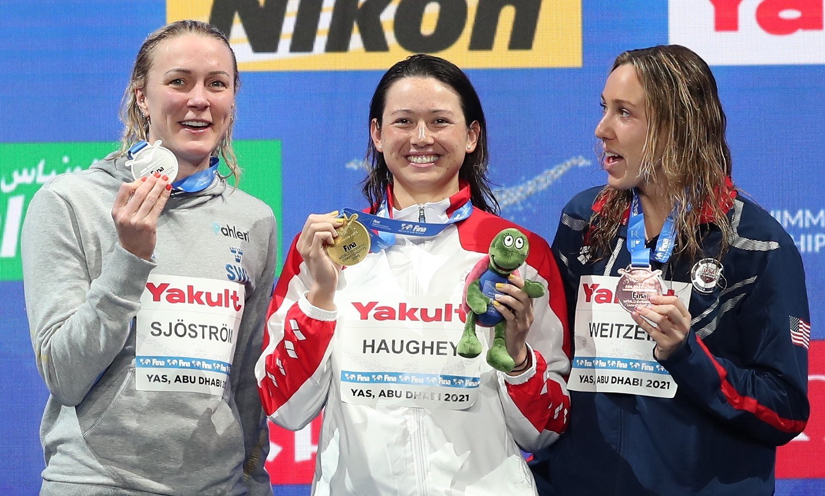 Siobhan Haughey (centre) holds up her 100m freestyle gold medal at the 2021 world short-course championships, with silver medallist Sarah Sjostrom (left) and bronze medallist Abbey Weitzeil. Photo: EPA-EFE