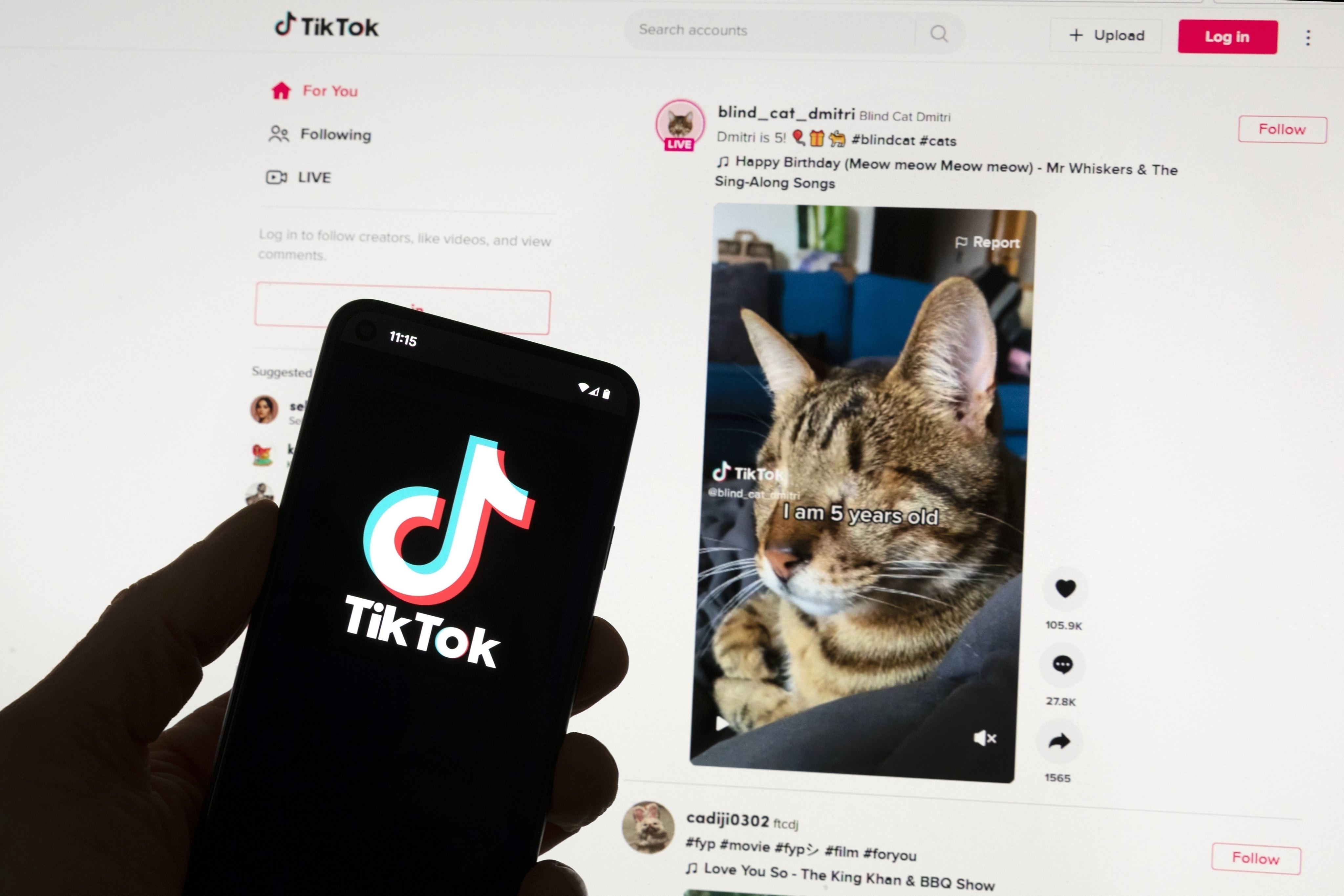 The TikTok logo is seen on a mobile phone in front of a computer screen which displays the TikTok home screen,  March 18, 2023. Photo: AP