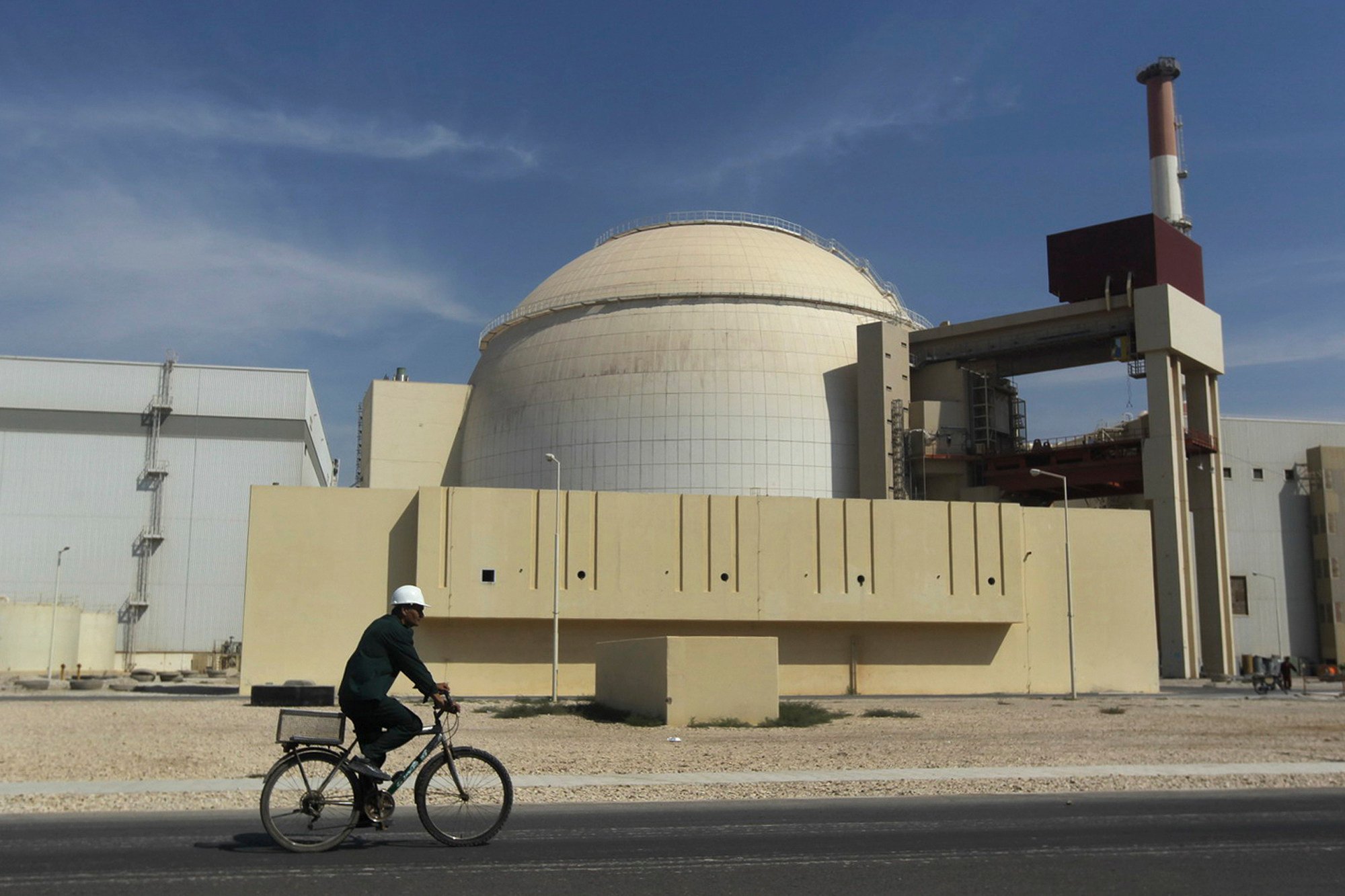 A worker rides a bike in front of the reactor building of the Bushehr nuclear power plant in Iran in October 2010. Photo: AP