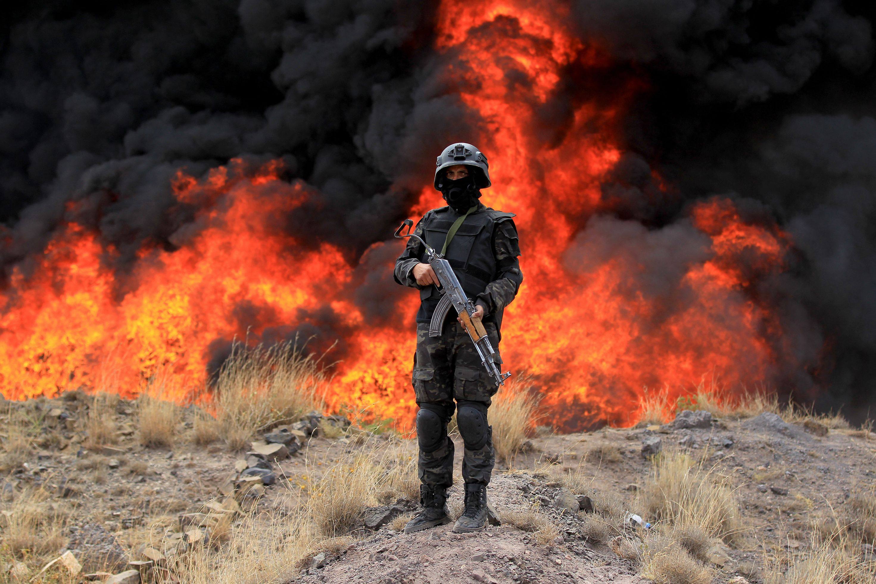 A member of the security forces affiliated with Yemen’s Houthi rebels stands guard in front of a bonfire incinerating seized narcotic substances, in Sanaa on Saturday. Photo: AFP