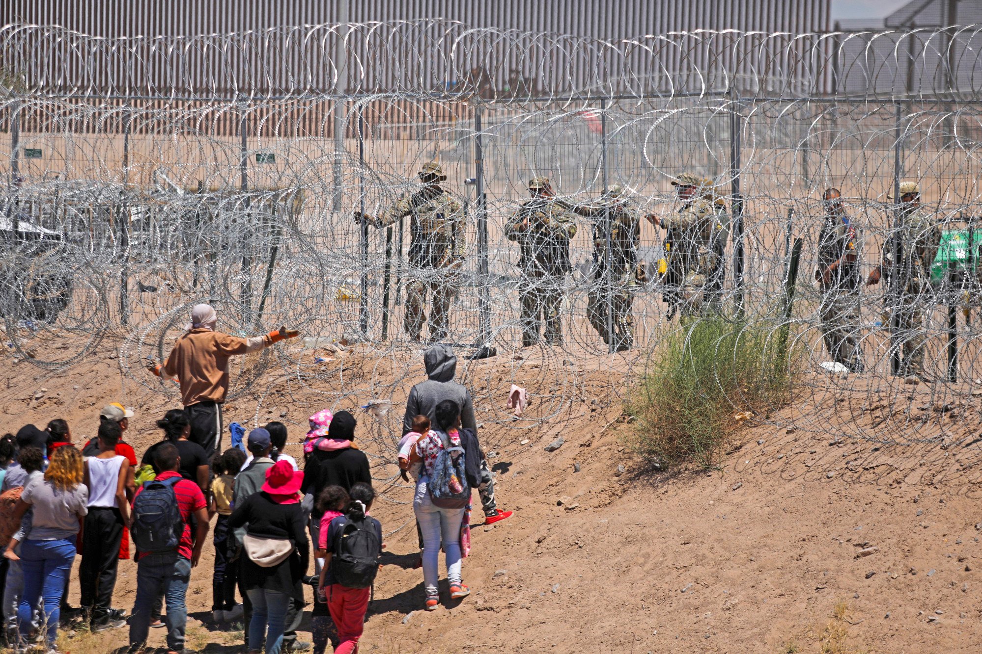 Migrants seek to enter the United States through a barbed wire fence at the border with Mexico earlier this year. Photo: AFP/Getty Images/TNS