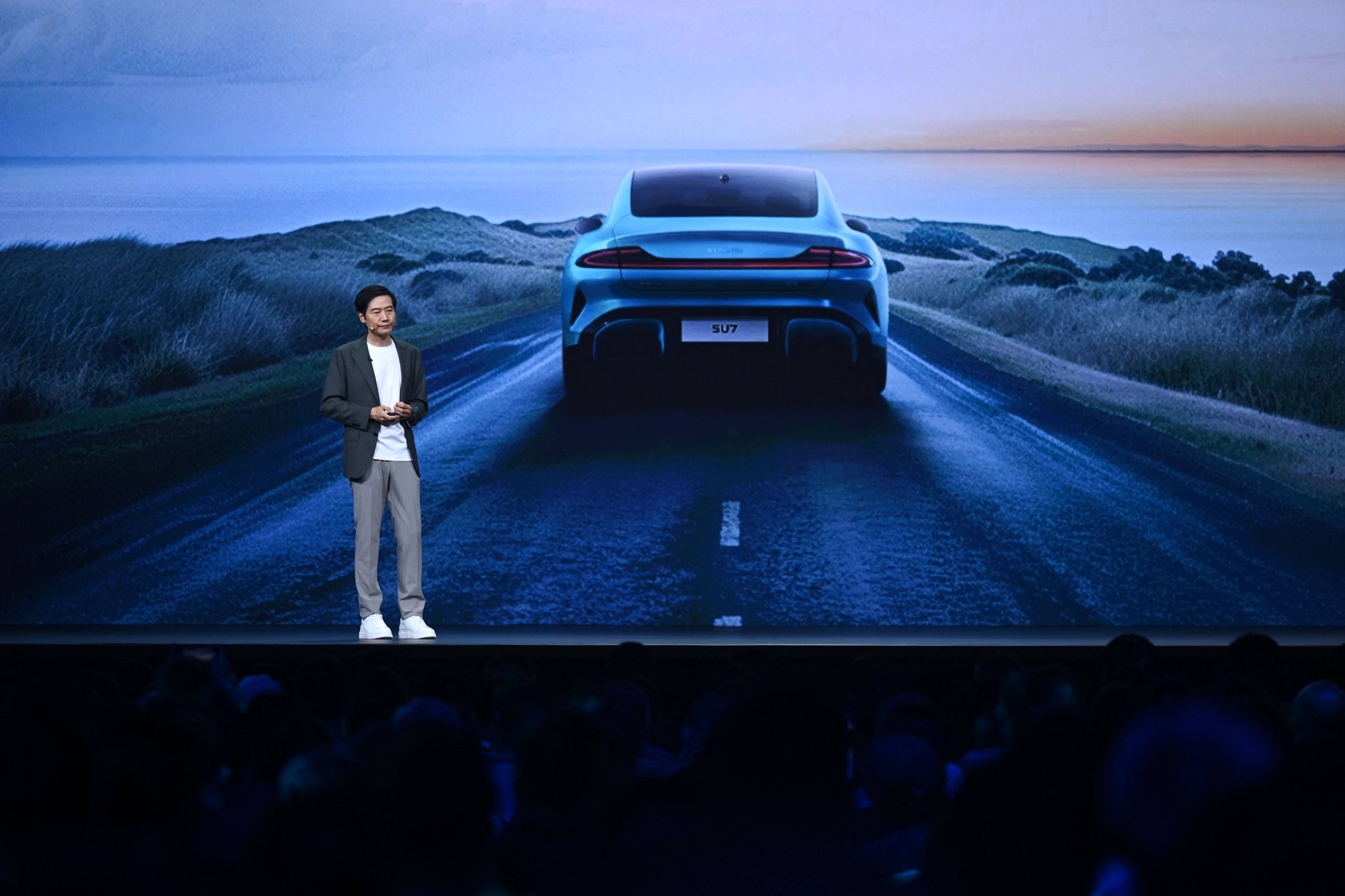 Xiaomi founder and CEO Lei Jun speaks in front of an image of the SU7 sedan at an event in Beijing on July 19. Photo: AFP