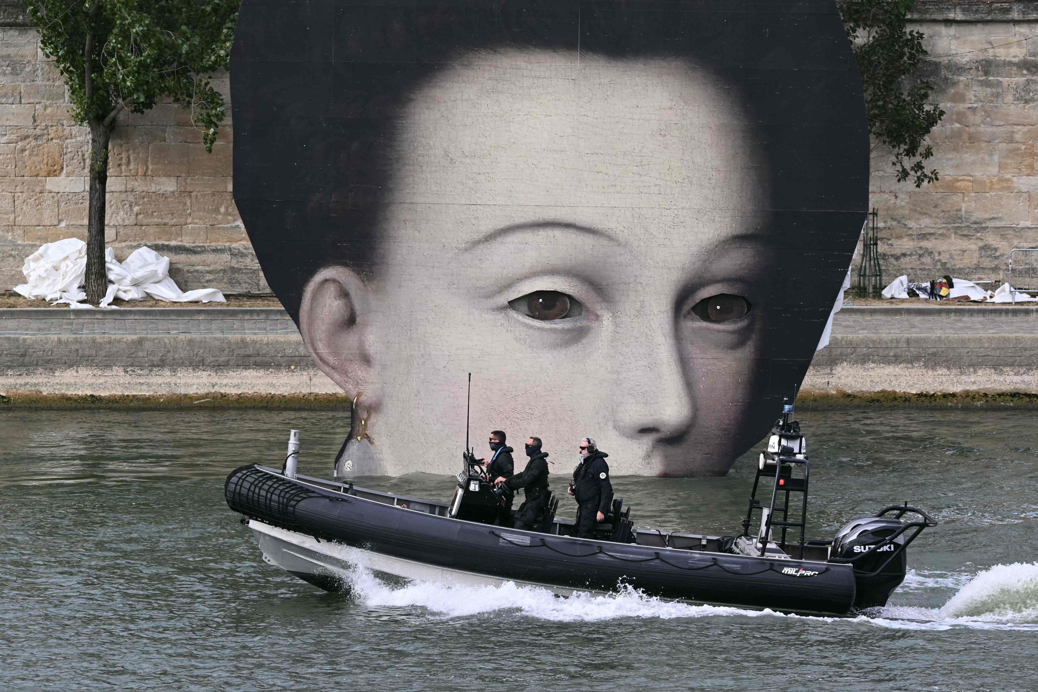 A police boat patrols the Seine river next to a panel depicting a pictorial detail ahead of the opening ceremony of the Paris Olympics, which will have 45,000 security guards in attendance. Photo: AFP