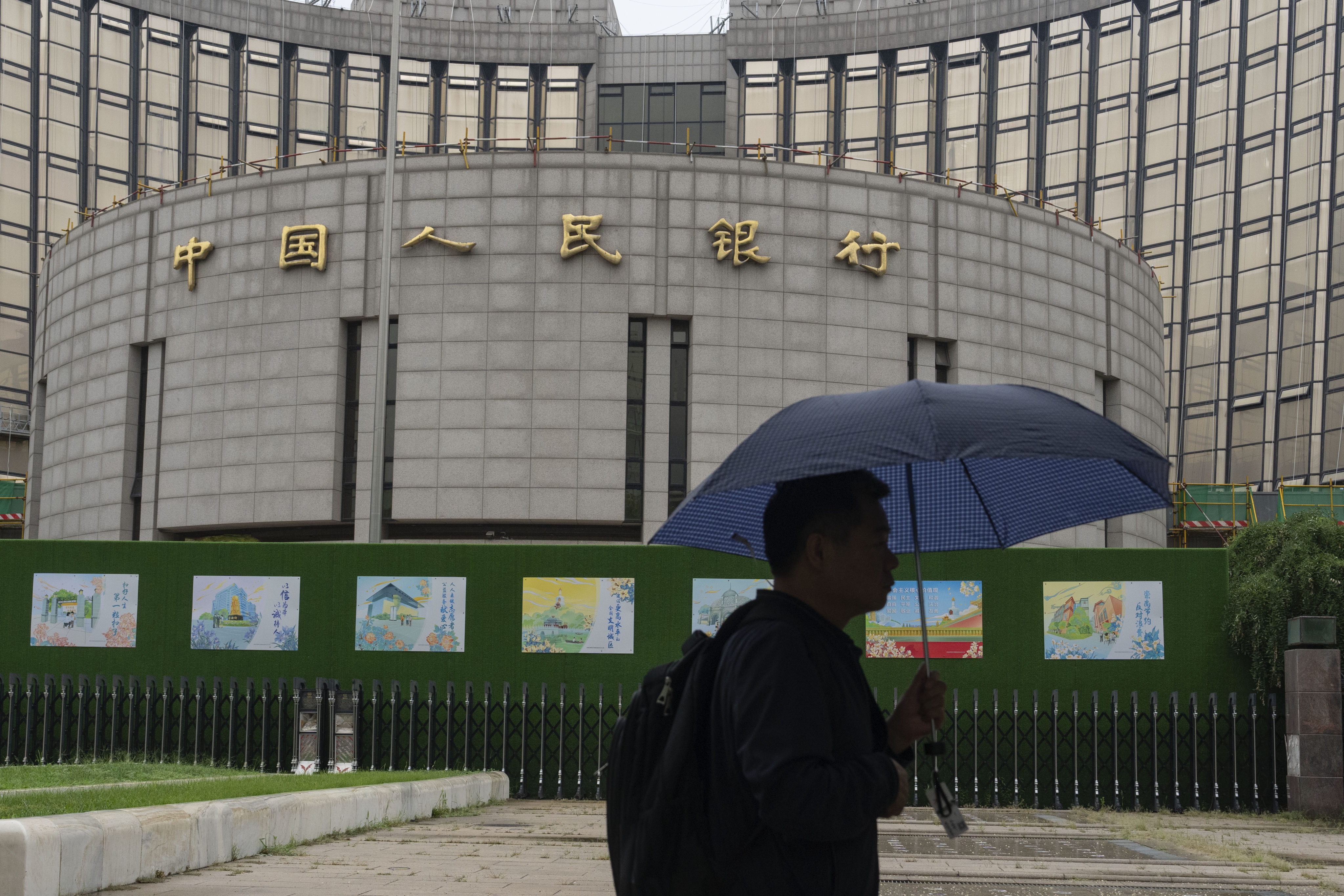 A man with an umbrella passes by China’s central bank in Beijing. Photo: AP