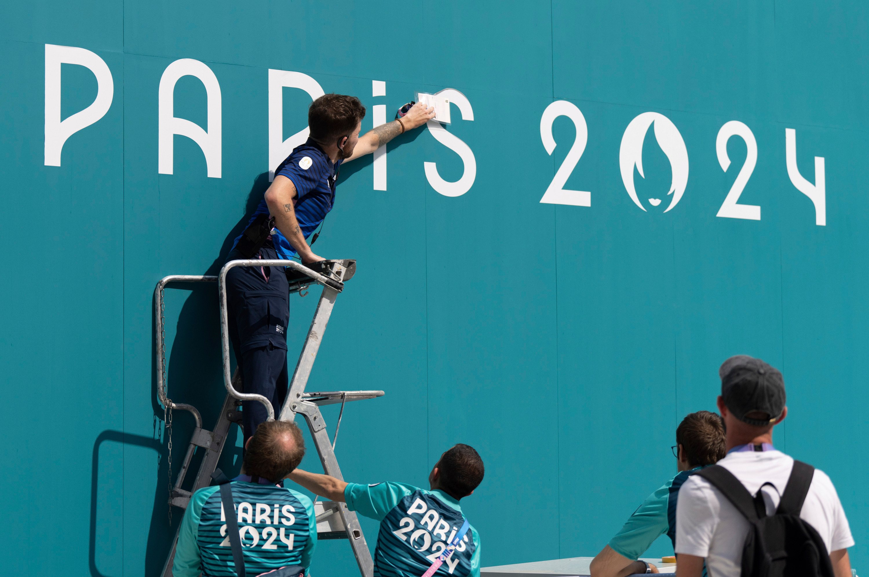 A volunteer fixes a sign in the Olympic Village in Paris. Photo: AP