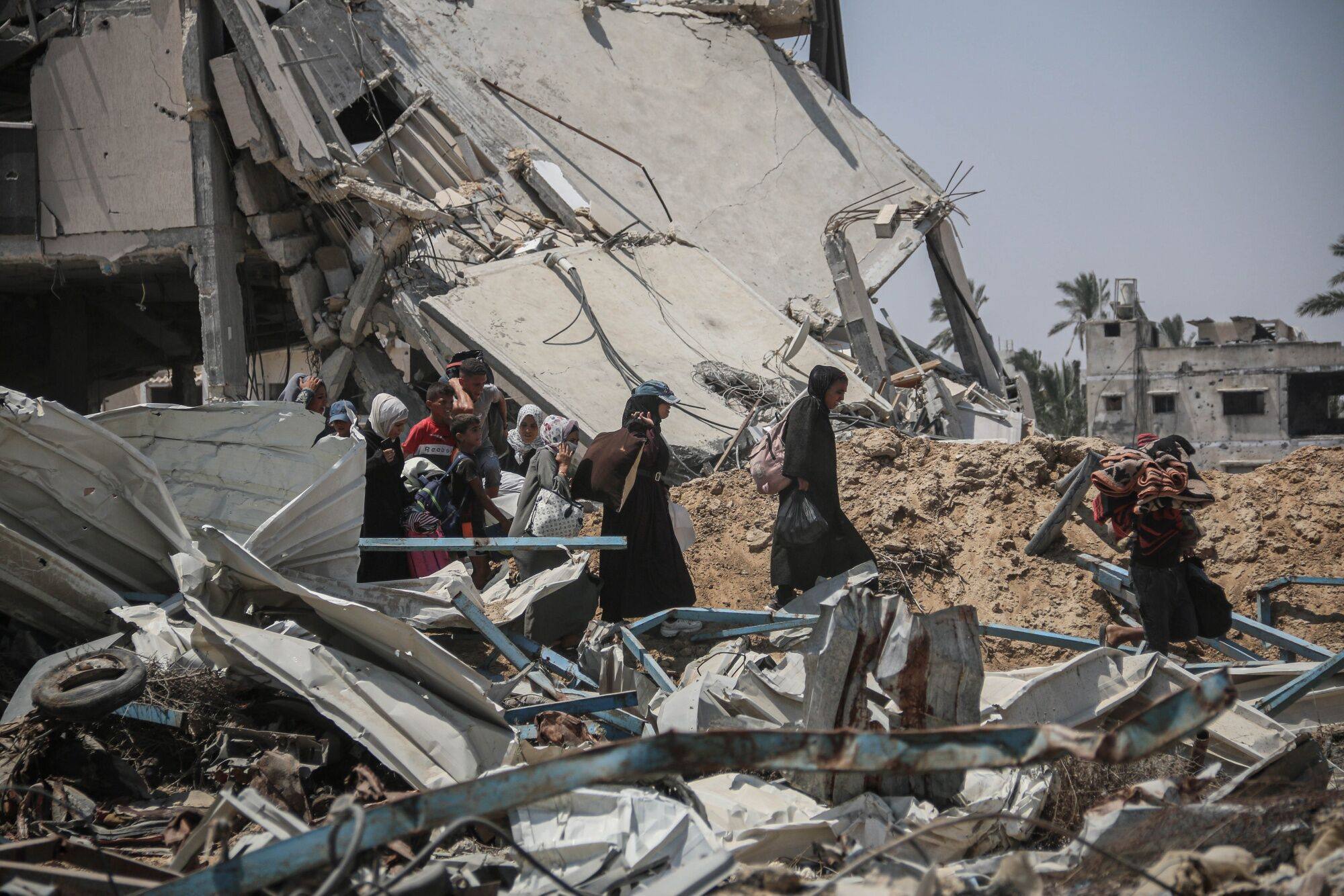 Displaced Palestinians pass destroyed buildings as they leave the eastern neighbourhoods following Israeli military orders to evacuate parts of the city in Khan Younis, southern Gaza. Photo: Bloomberg