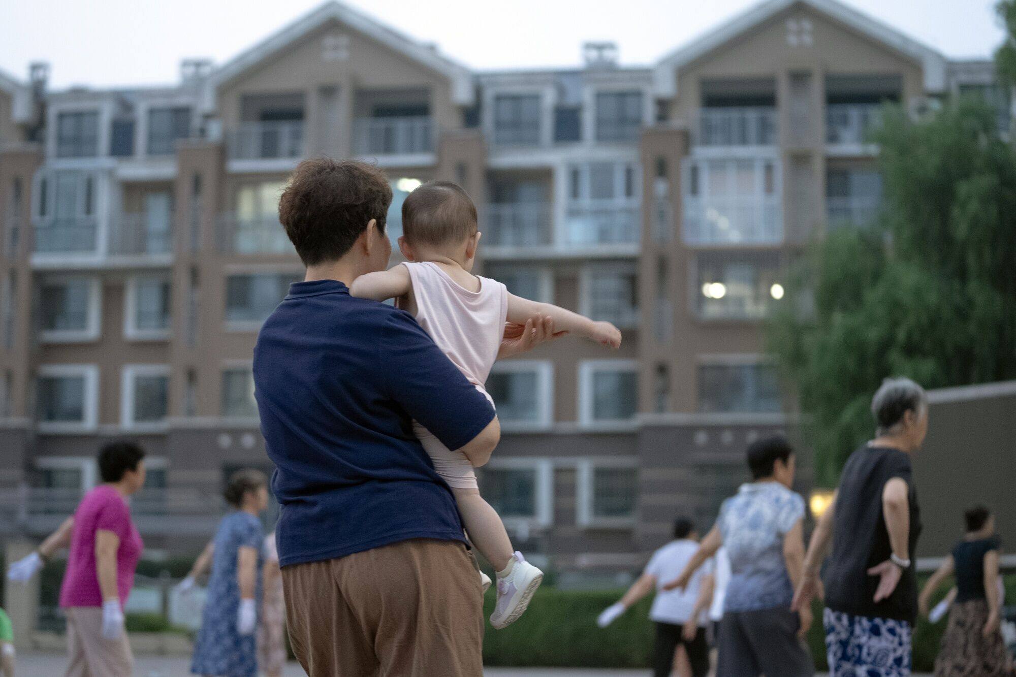 A woman carries a child at a park in Beijing. China’s population shrank by 2 million people last year, a trend that looks set to continue. Photo: Bloomberg