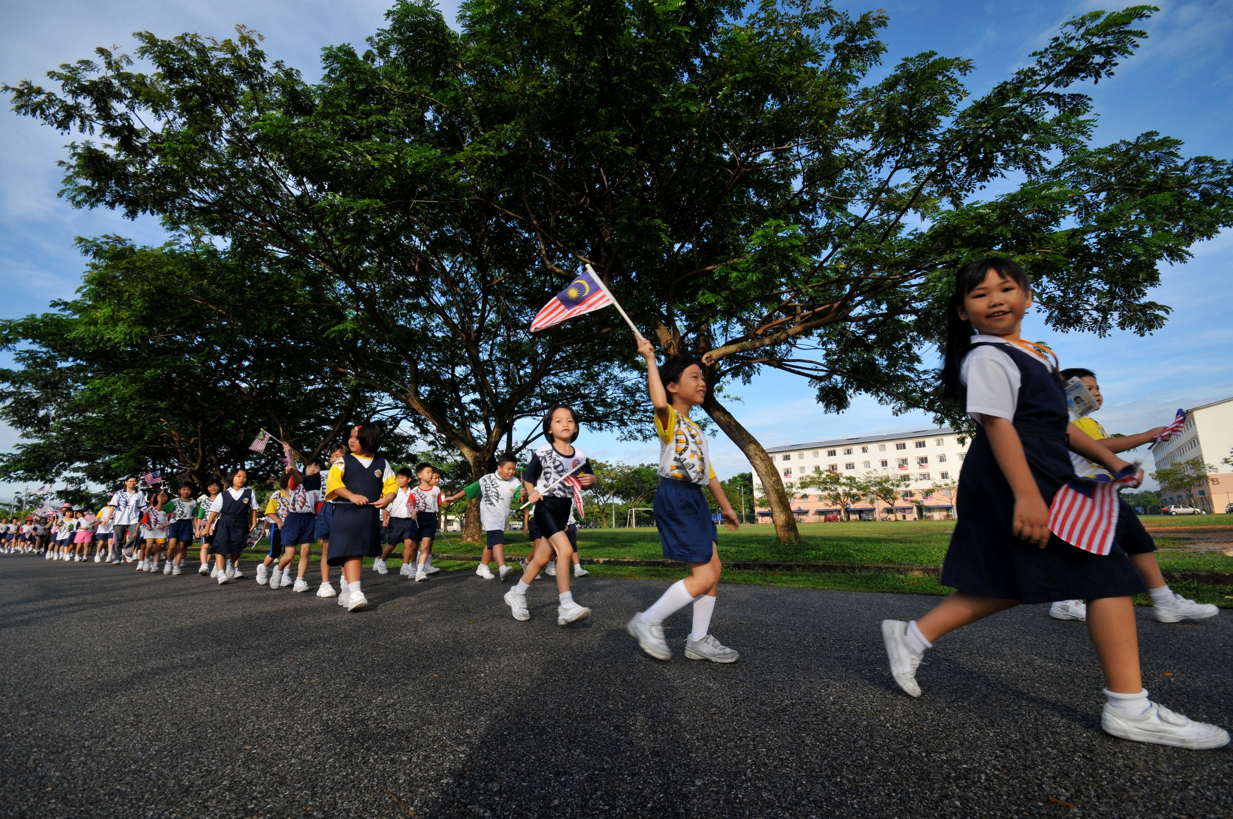 Malaysian school children waving the national flag. National schools in Malaysia teach in Malay and English while vernacular schools offer lessons in Mandarin and Tamil. Photo: Malaysian Chinese Association