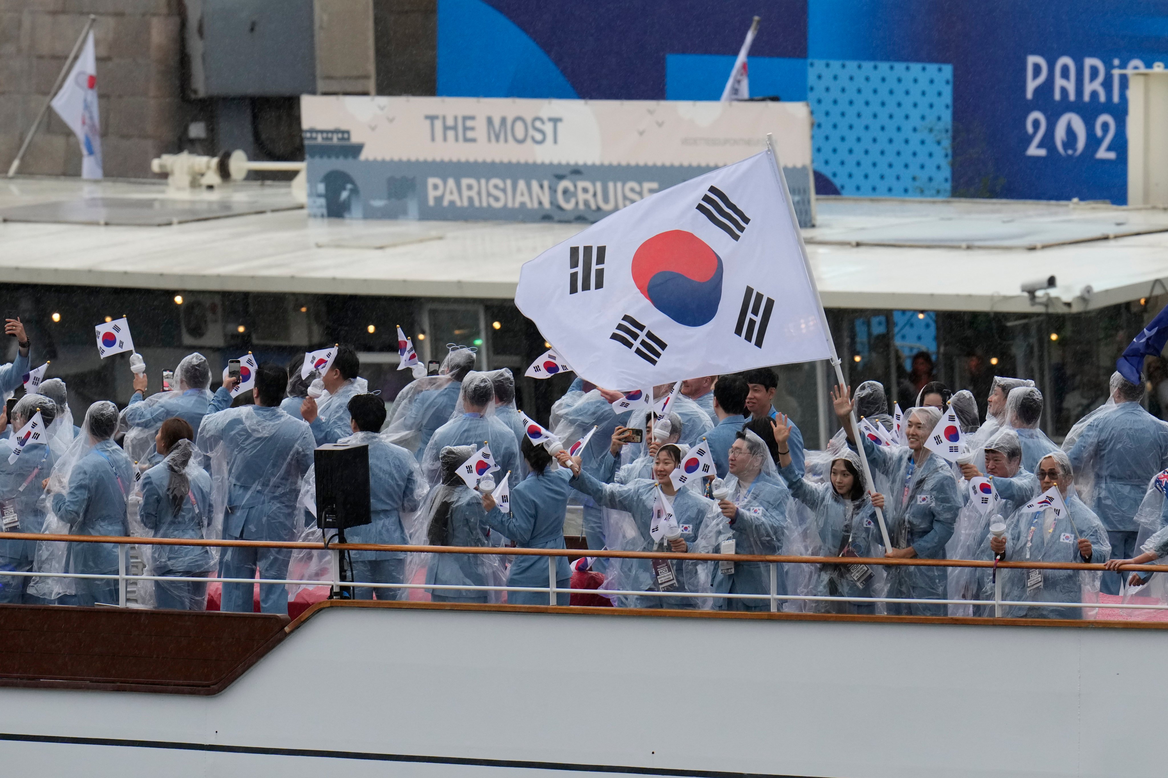 South Korea’s delegation protect themselves from the rain as they travel across the River Seine at the Paris Olympics opening ceremony. Photo: AP