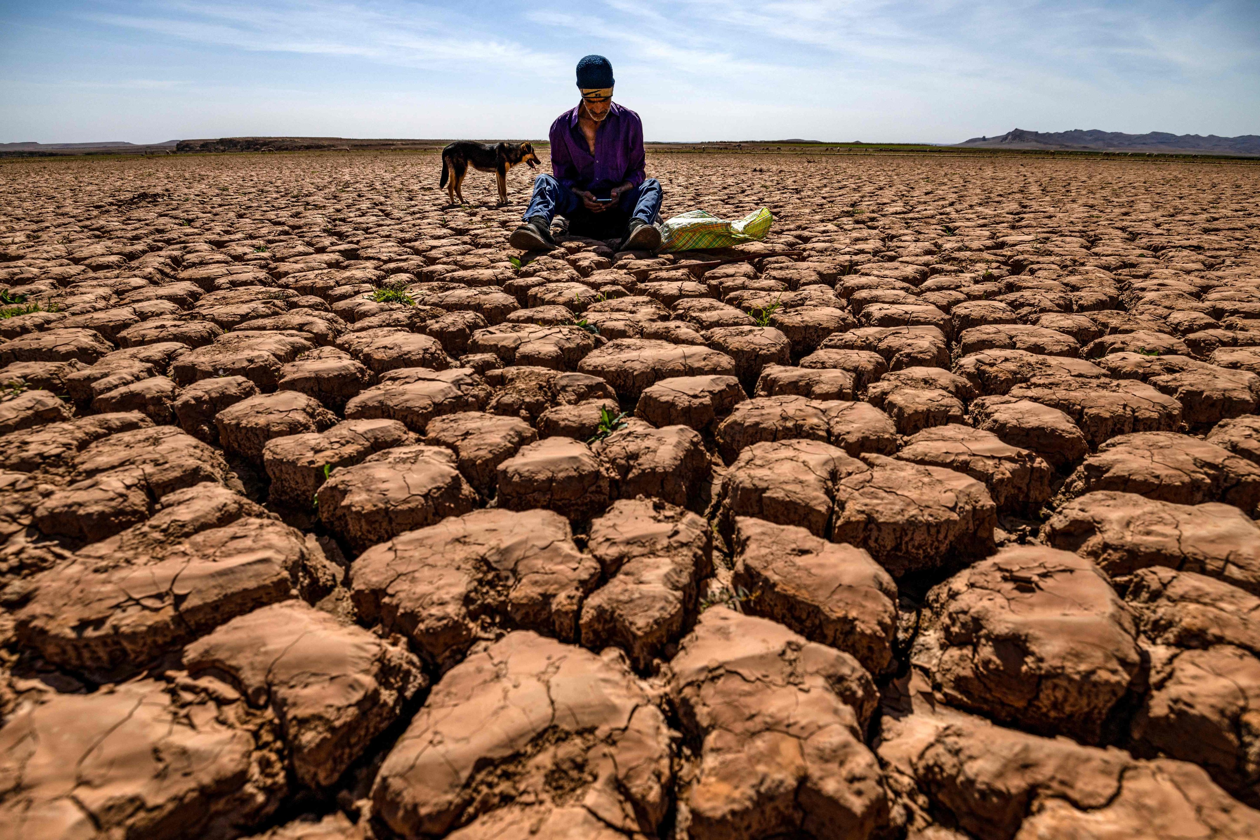 A shepherd sits on cracked earth at Al-Massira dam in Ouled Essi Masseoud village, Morocco. The country is in its sixth consecutive year of drought, according to the health ministry on Thursday. Photo: AFP Photo: AFP