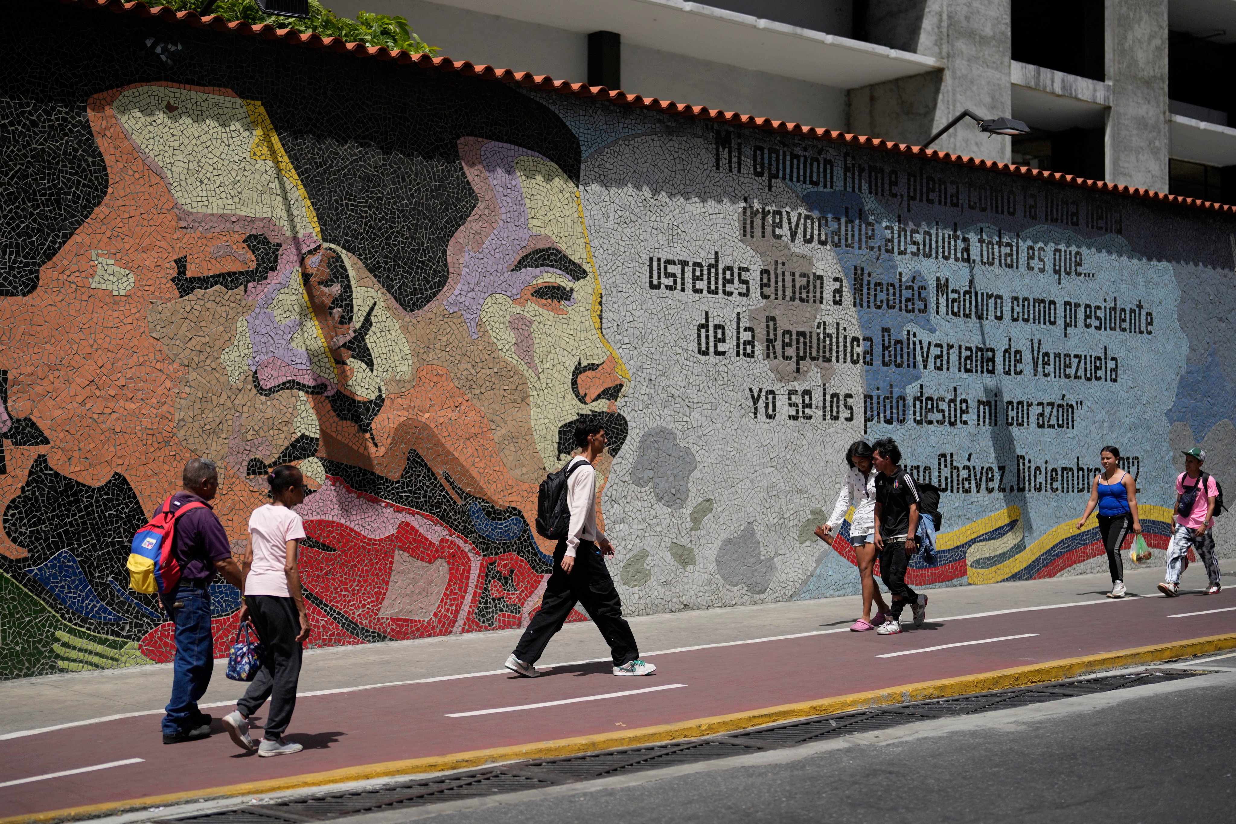 People walk past in front of a mural of late Venezuelan President Hugo Chavez and Venezuelan President Nicolas Maduro in Caracas. Photo: AP