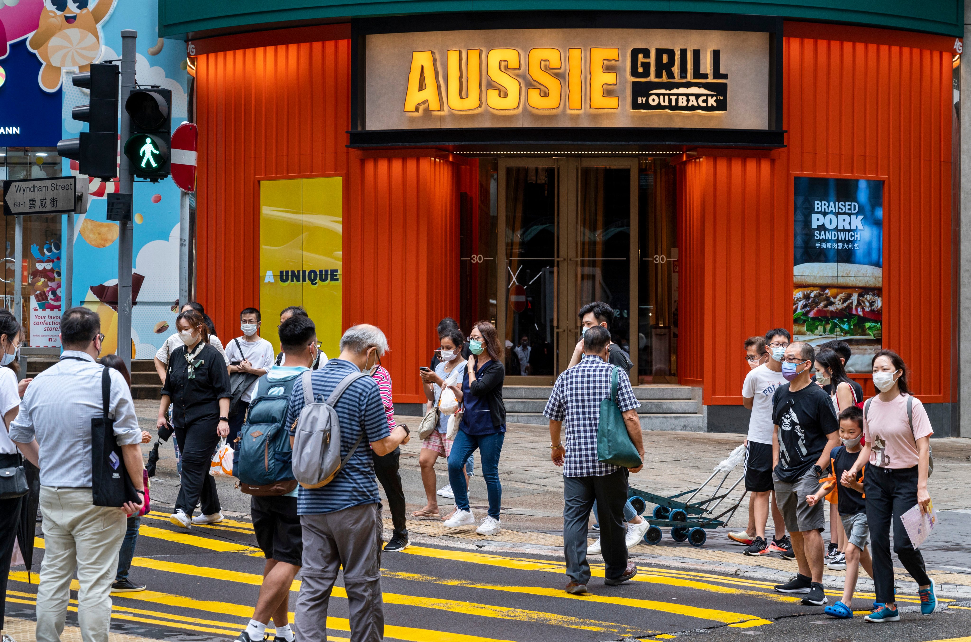 Pedestrians cross the street in front of the Australian-themed American casual dining restaurant chain by Outback Steakhouse, Aussie Grill, in Hong Kong. Photo: Getty Images