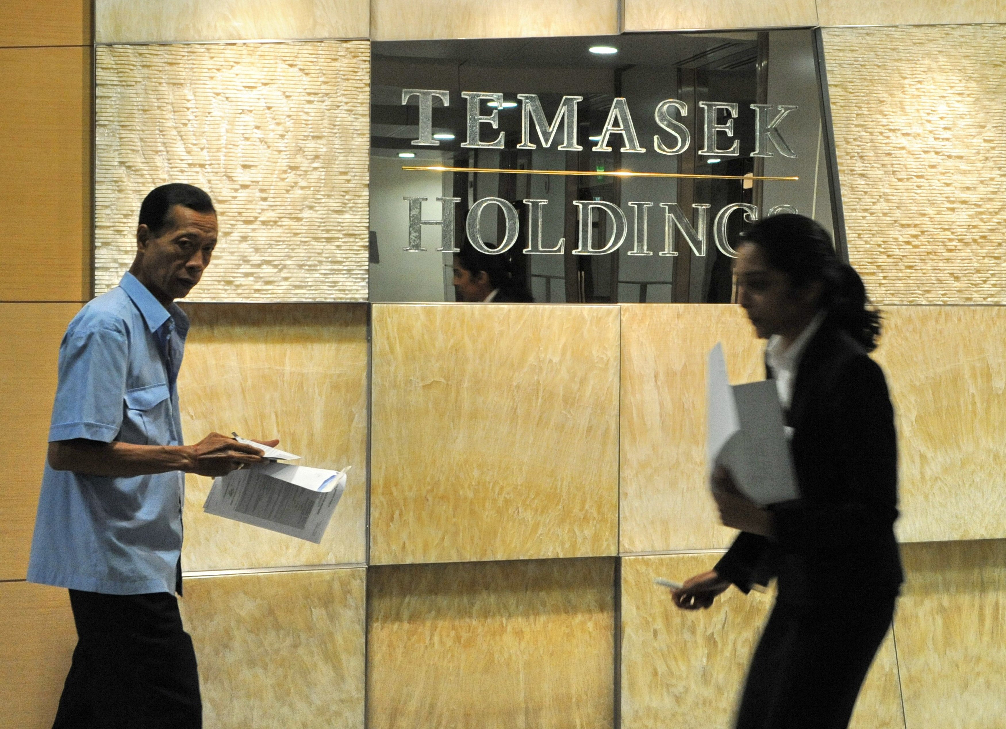 Office workers walk past Singapore state-linked investment firm Temasek Holdings sign in Singapore. Photo: AFP 