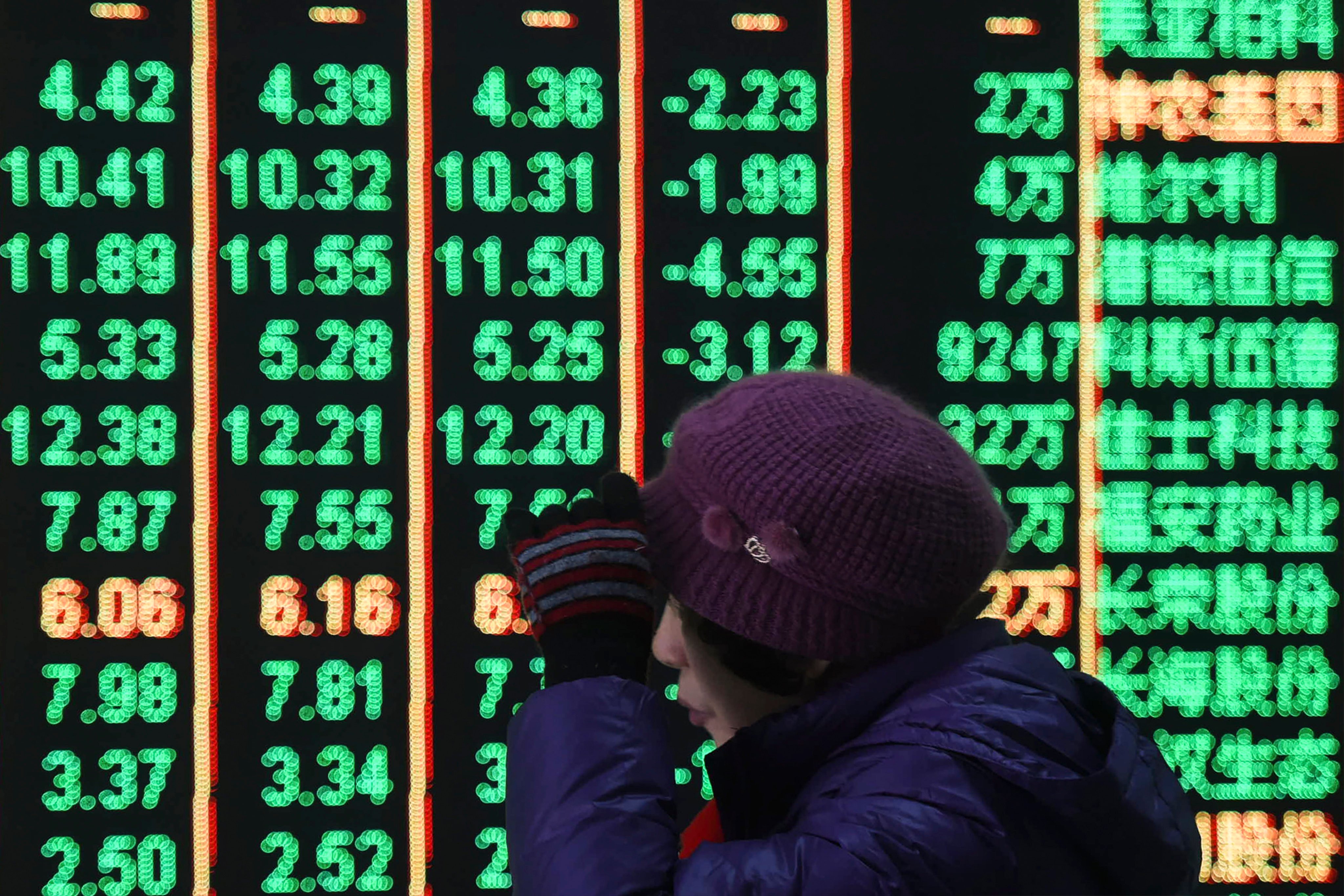 A woman walks in front of an electronic screen displaying stock prices at a brokerage house in Hangzhou in east China’s Zhejiang province. Photo: AP