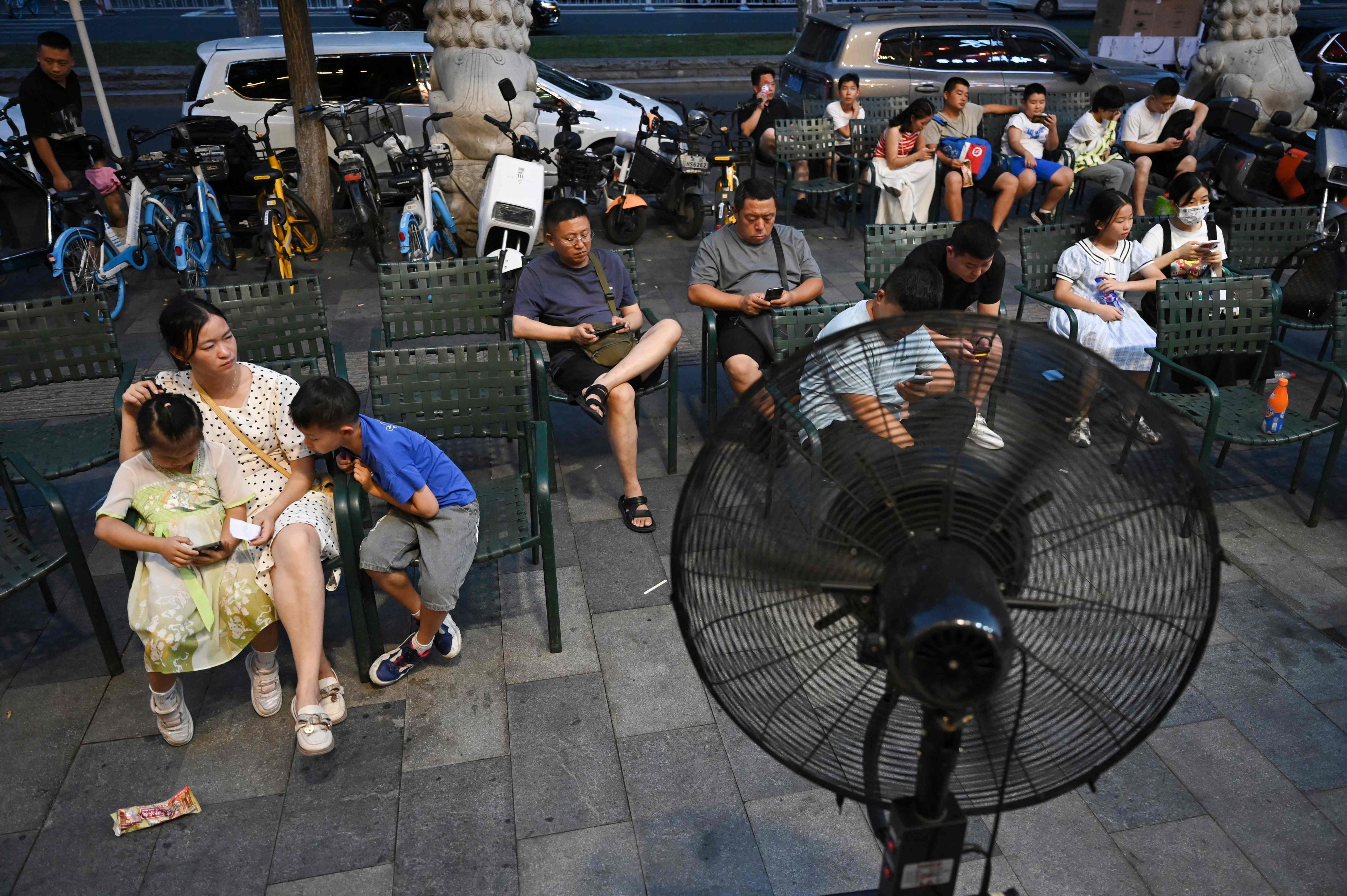 People sit in front of a fan as they wait for seats at a restaurant during heatwave conditions in Beijing. Photo: AFP