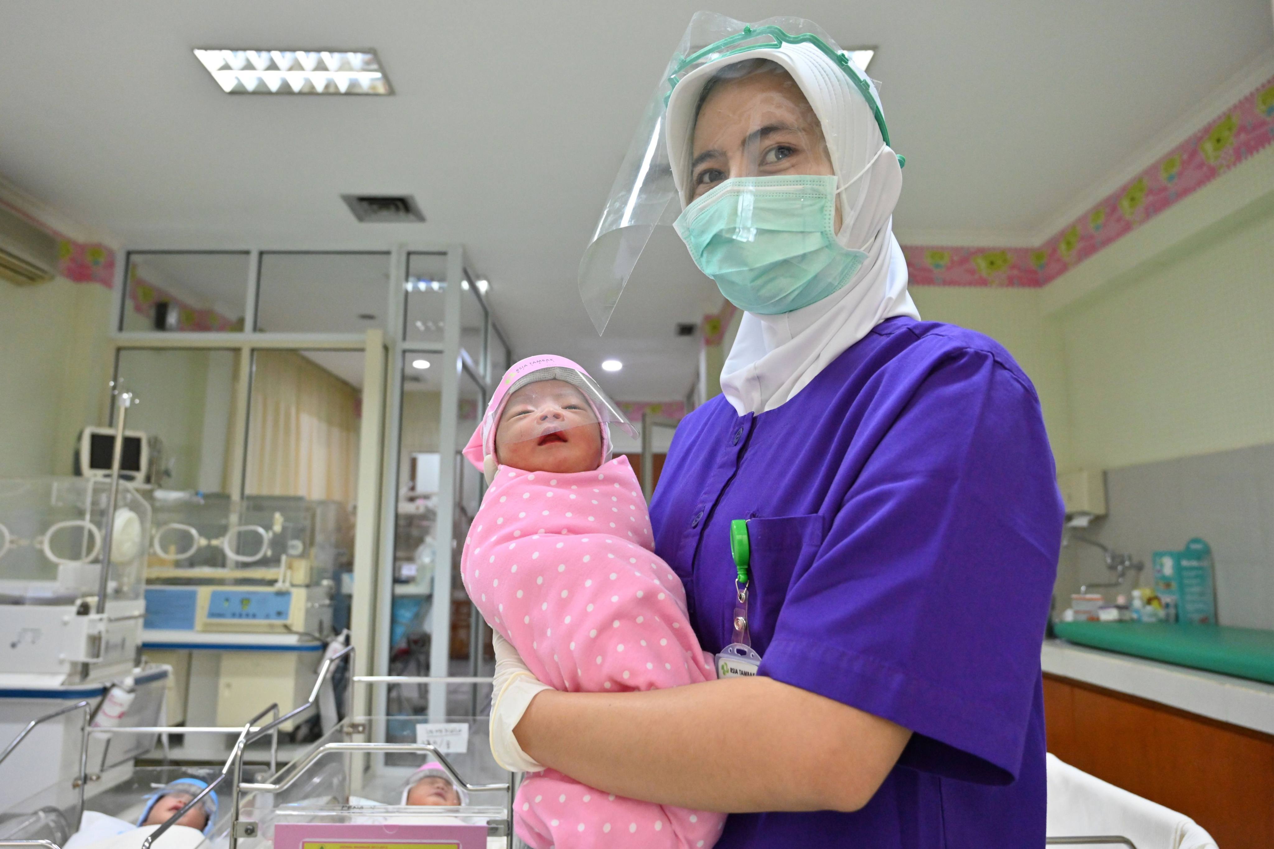 A nurse holds a newborn baby in the maternity ward of a Jakarta hospital. Photo: AFP