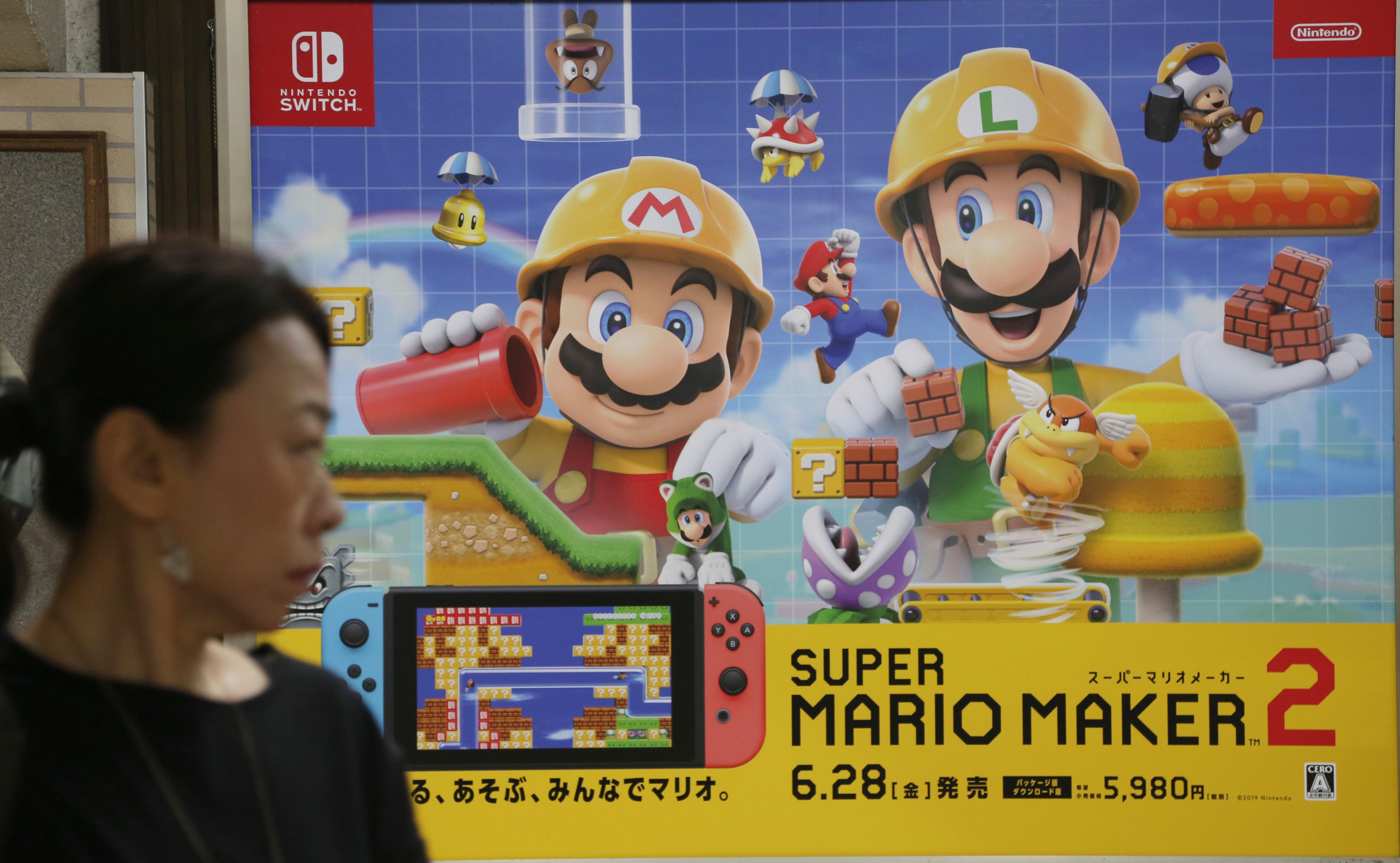 A woman walks by a Nintendo advertisement for the game Super Mario Maker 2 on the Switch in Tokyo on July 9, 2019. Photo: AP