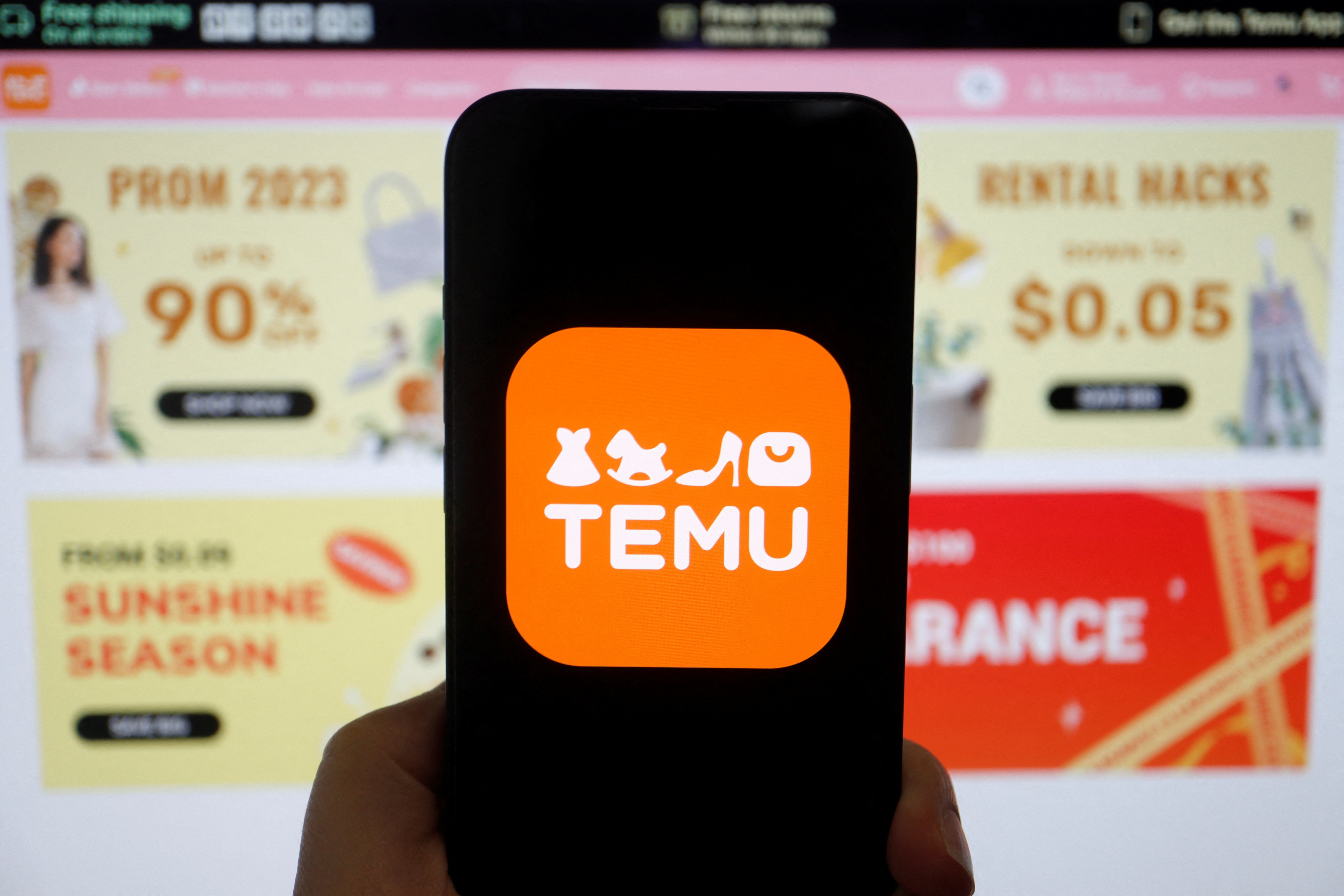 The logo of Temu, an e-commerce platform owned by PDD Holdings, seen on a mobile phone displayed in front of its website on April 26, 2023. Photo: Reuters