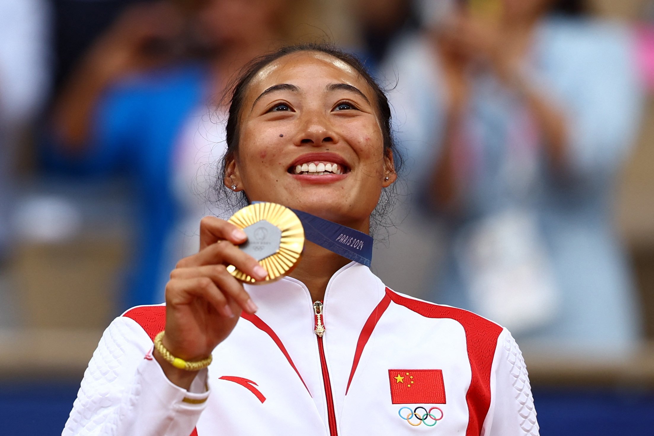 Gold medallist Zheng Qinwen looks to the sky as she poses with her medal. Photo: Reuters