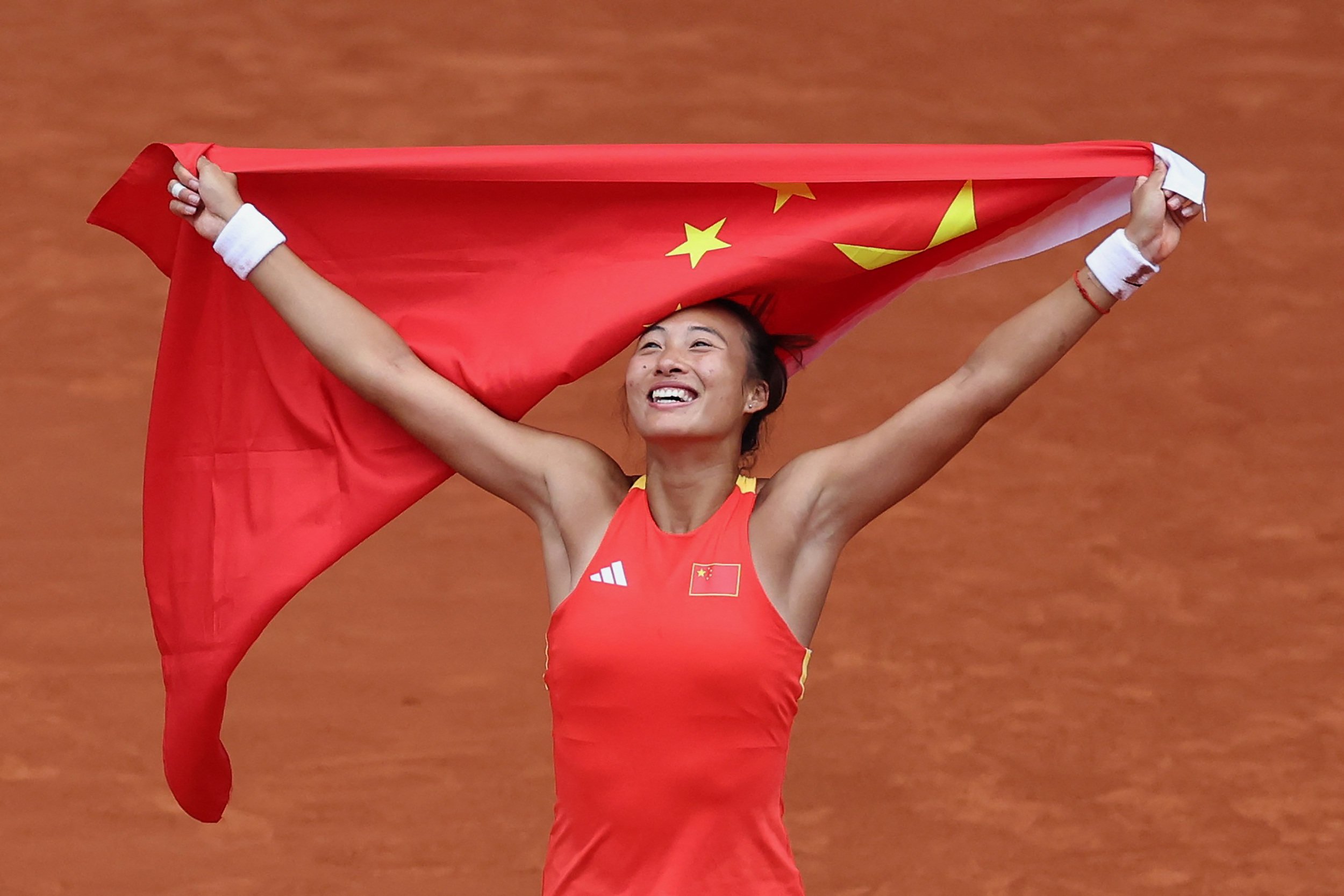 Zheng Qinwen celebrates with a Chinese flag after winning gold. Photo: Reuters